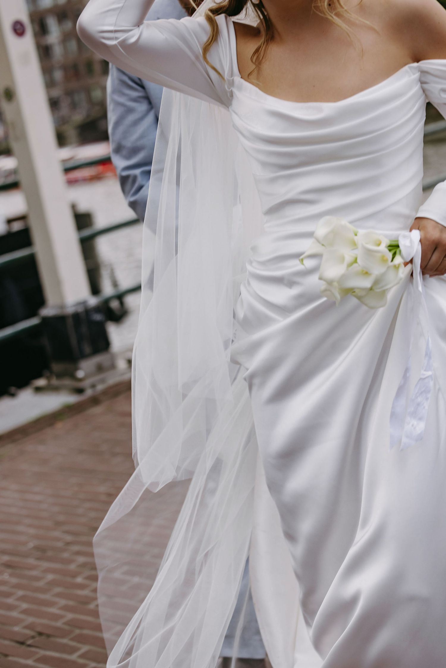 Close-up of white wedding dress details with delicate orchid flower accents.