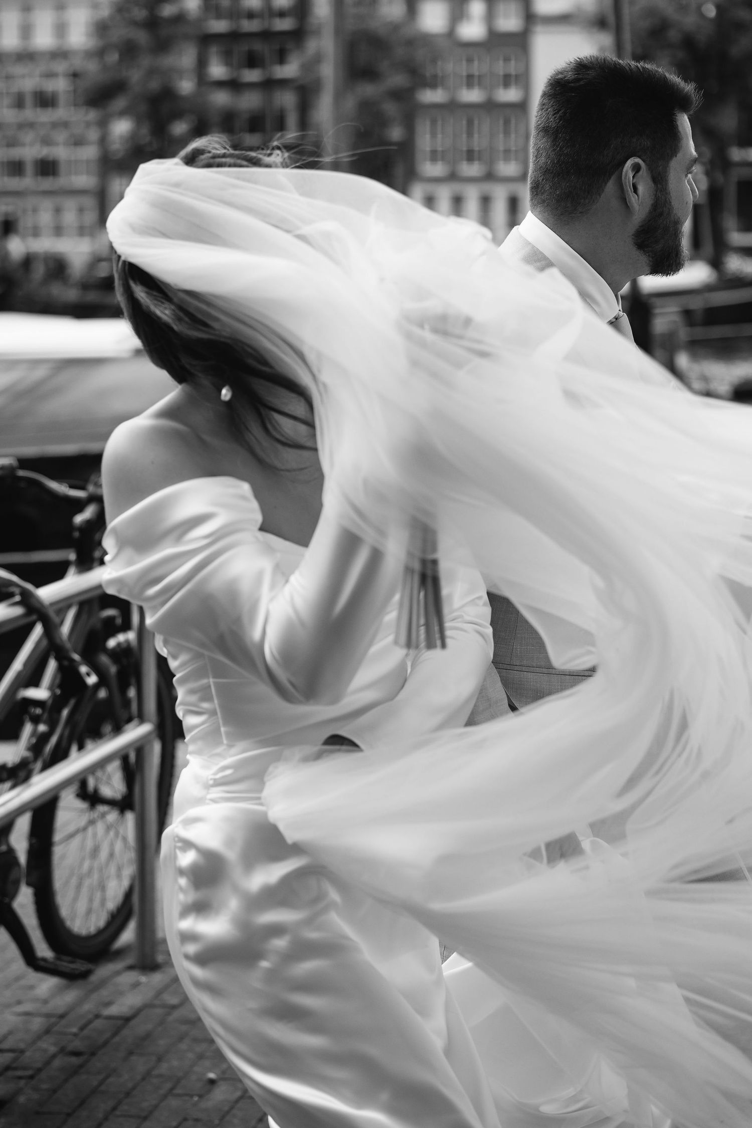 Flowing white fabric caught in motion against an urban street backdrop.