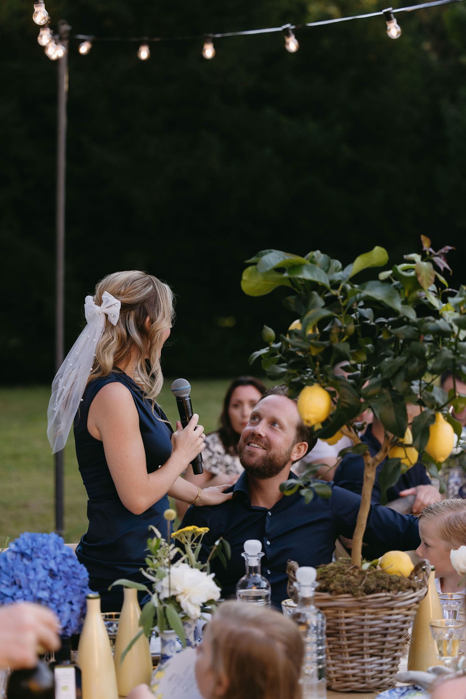 Outdoor dinner party under string lights with a lemon tree centerpiece and casual ambiance.