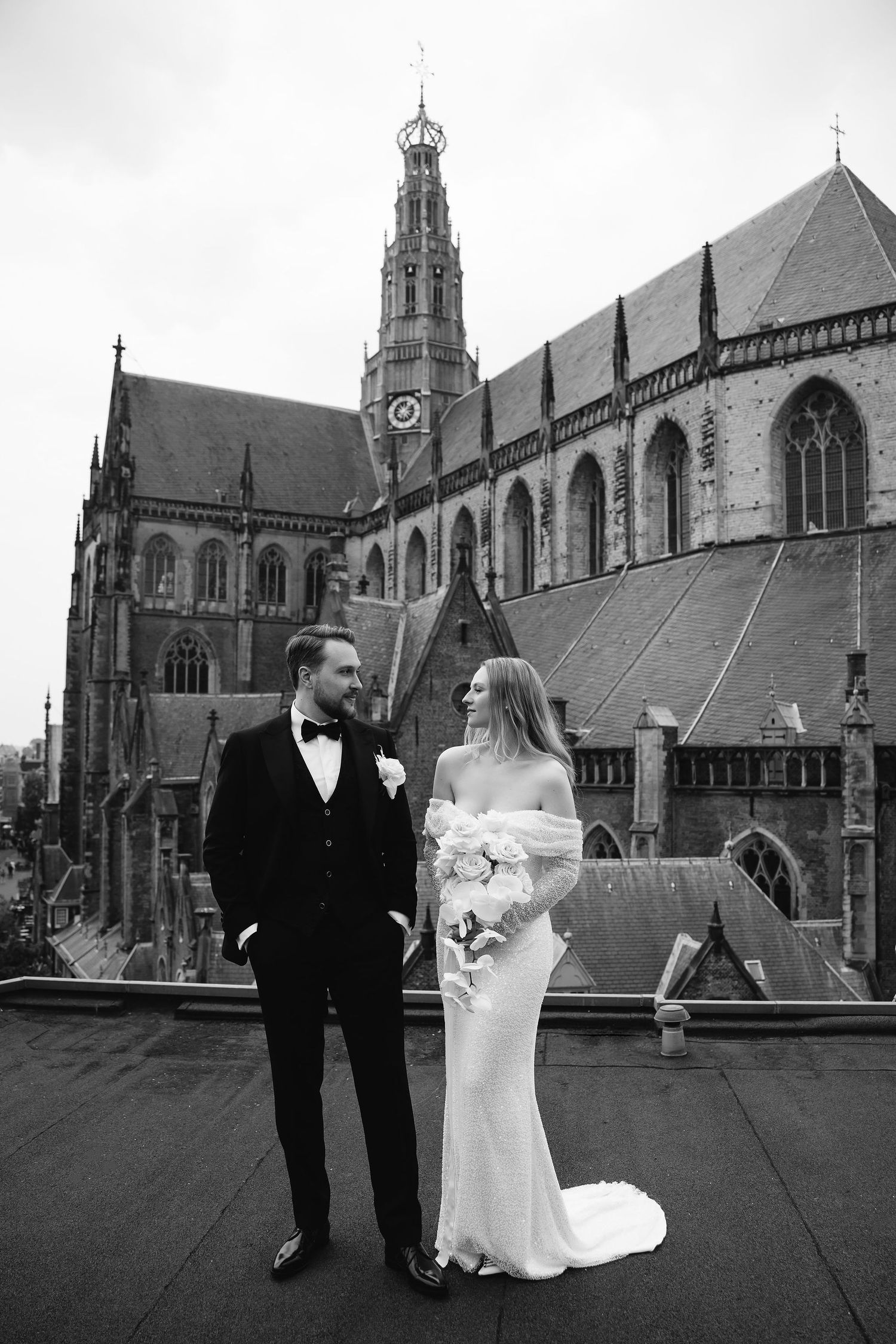 A couple in wedding attire standing in front of the historic St. Bavo Church in Haarlem on their special day.