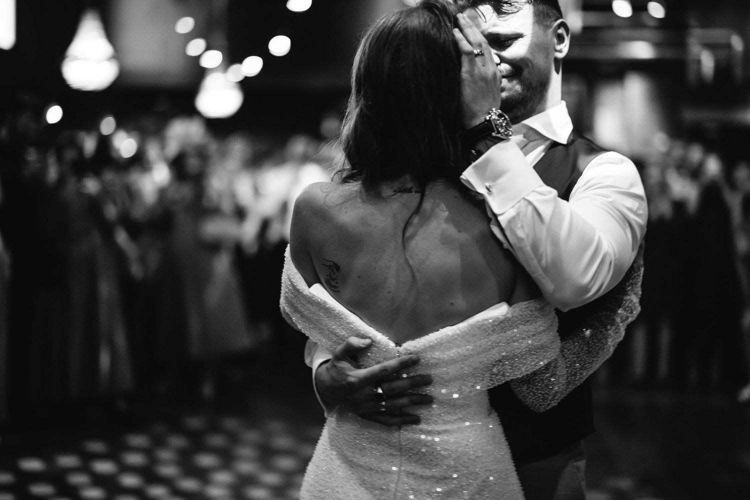 Couples dancing at an evening wedding reception with twinkling lights in the background.