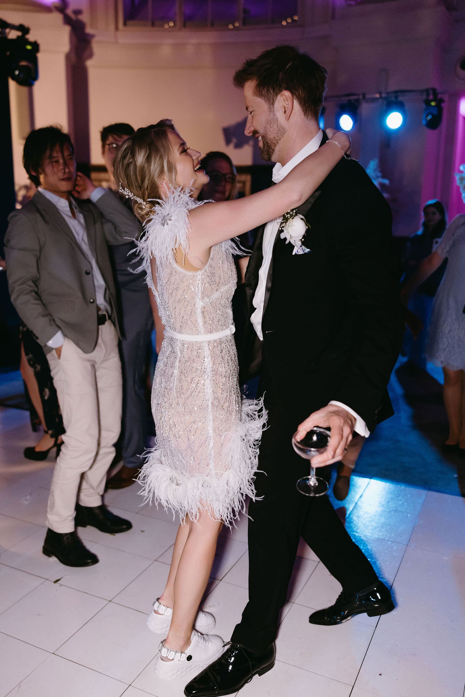 Dancing at wedding reception with purple lighting and feather-trimmed dress.