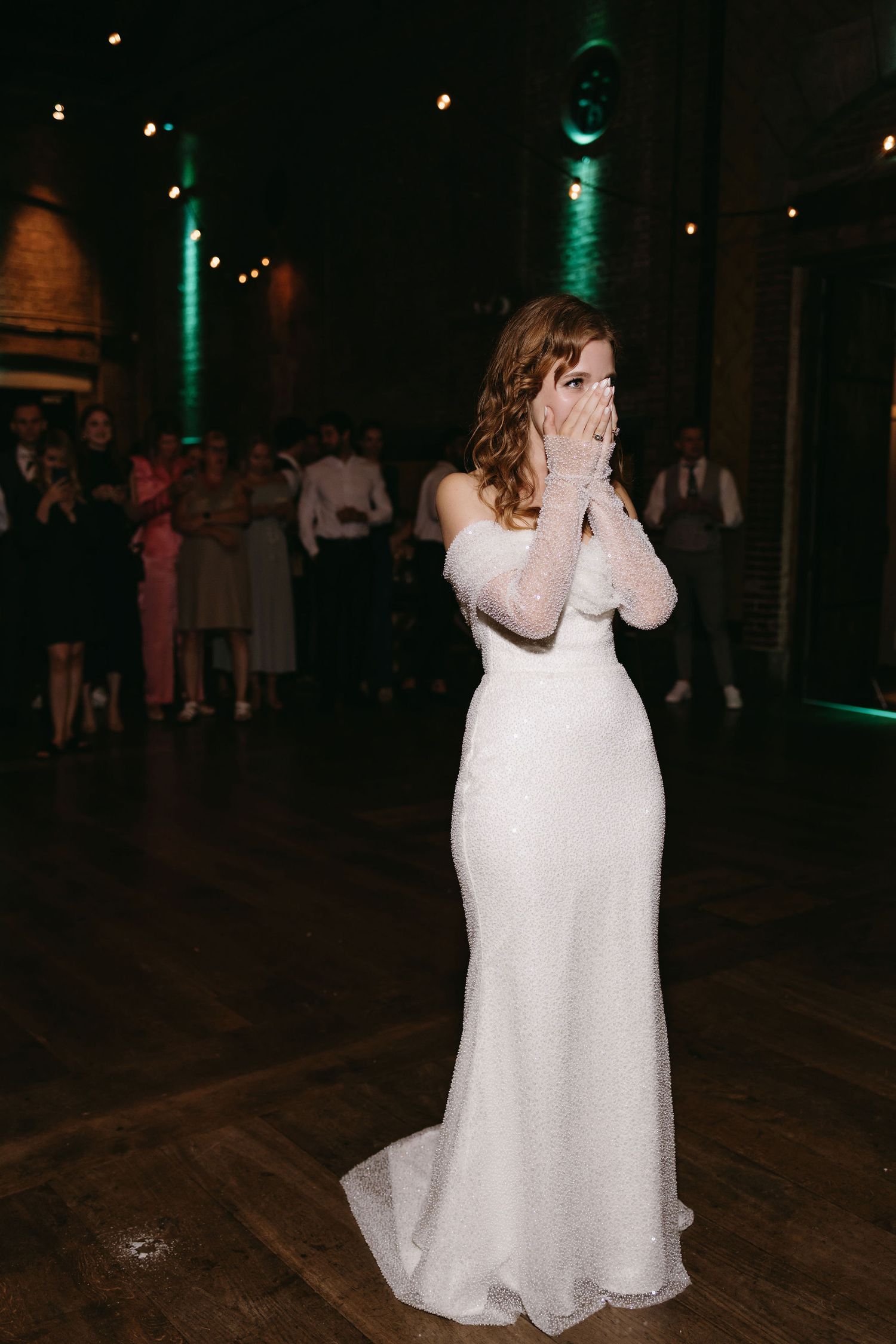 Emotional reactions during a wedding reception in a dark venue with green lighting.