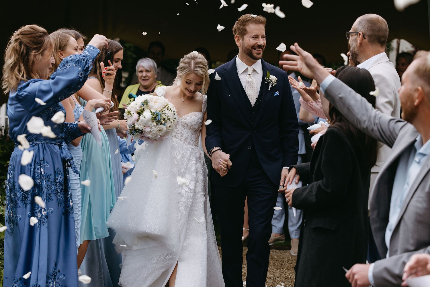Wedding celebration with guests throwing confetti as couple dances together.