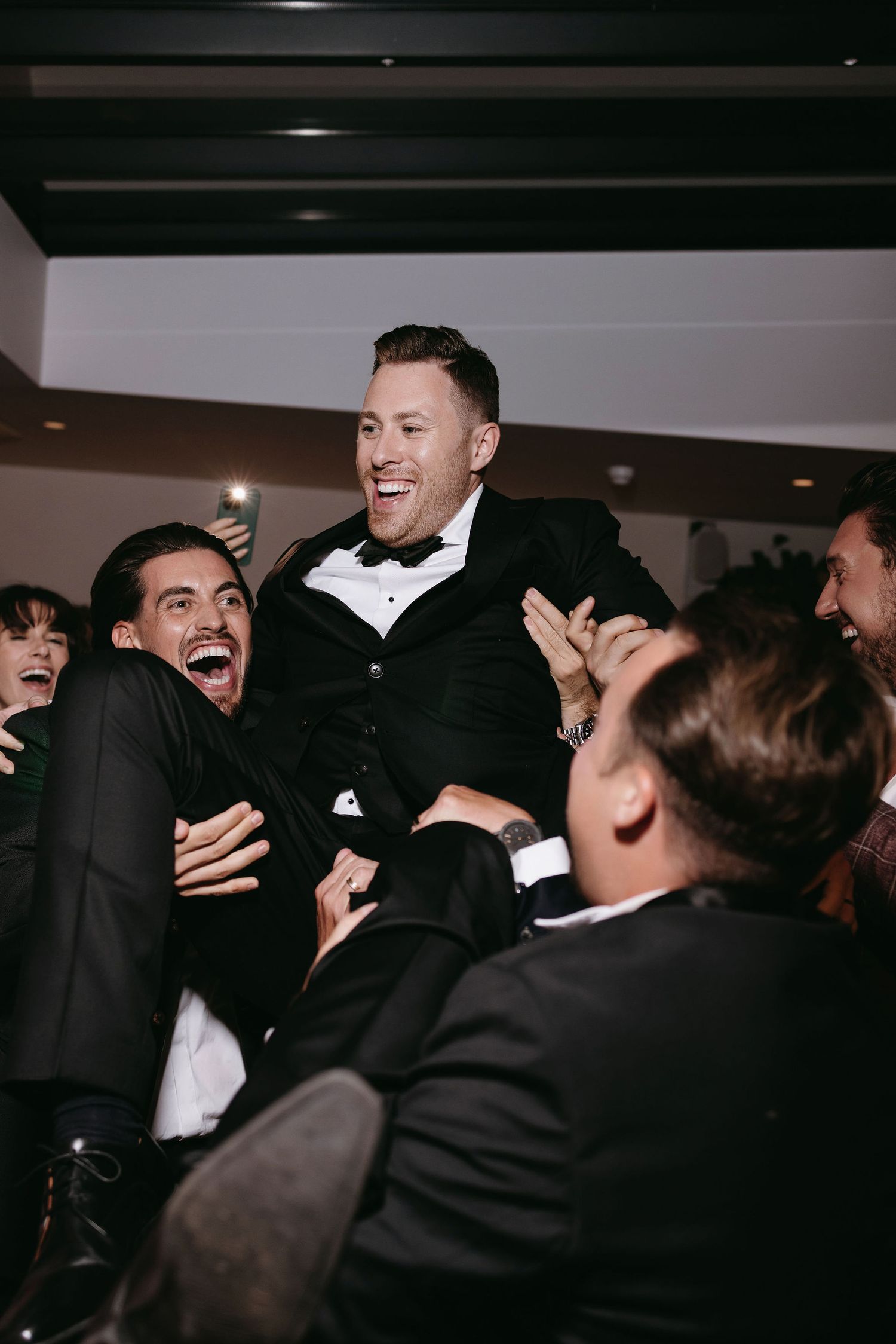 Groomsmen lifting and celebrating during wedding reception party.