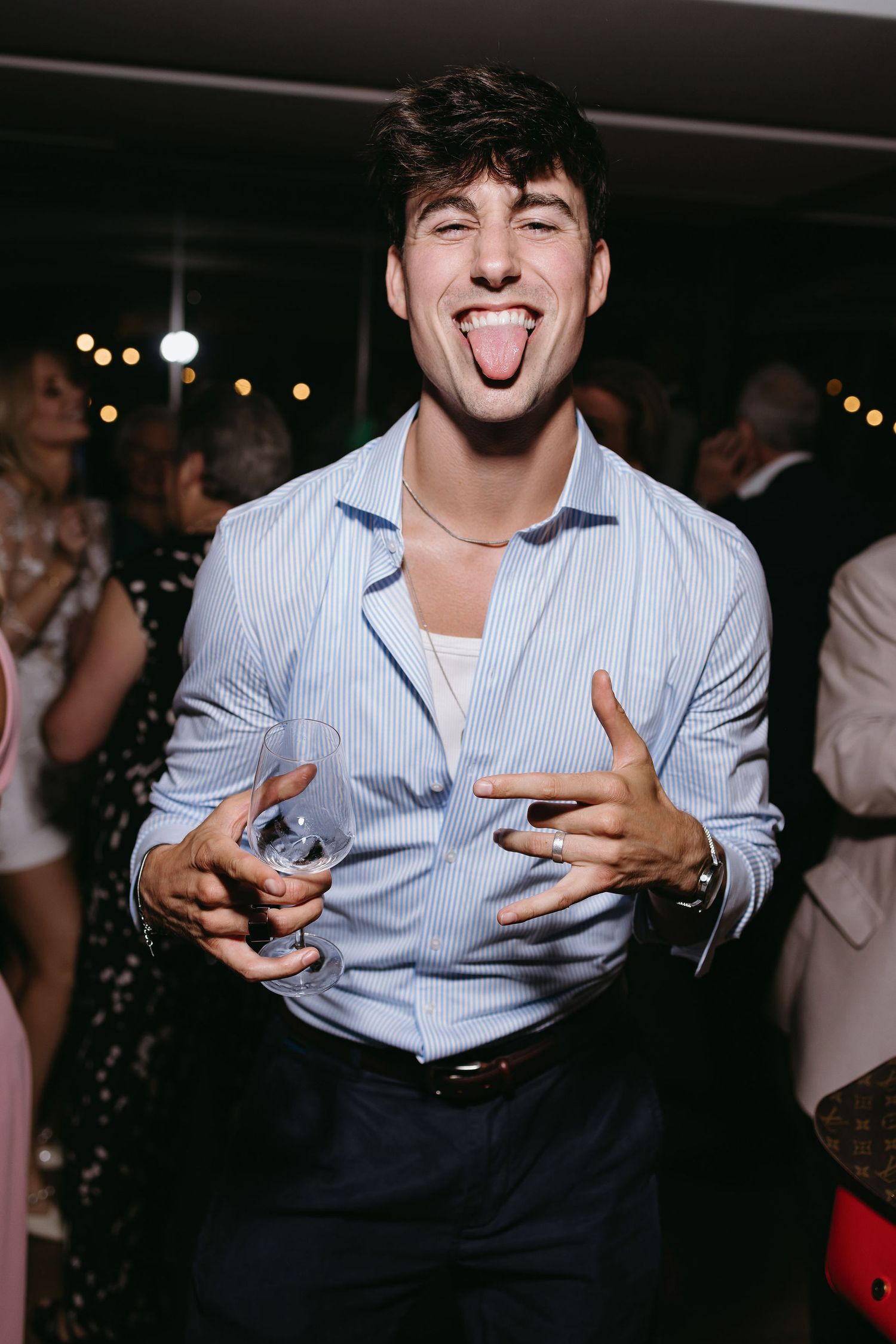 Wedding reception guests dancing and celebrating in blue button-down shirts.