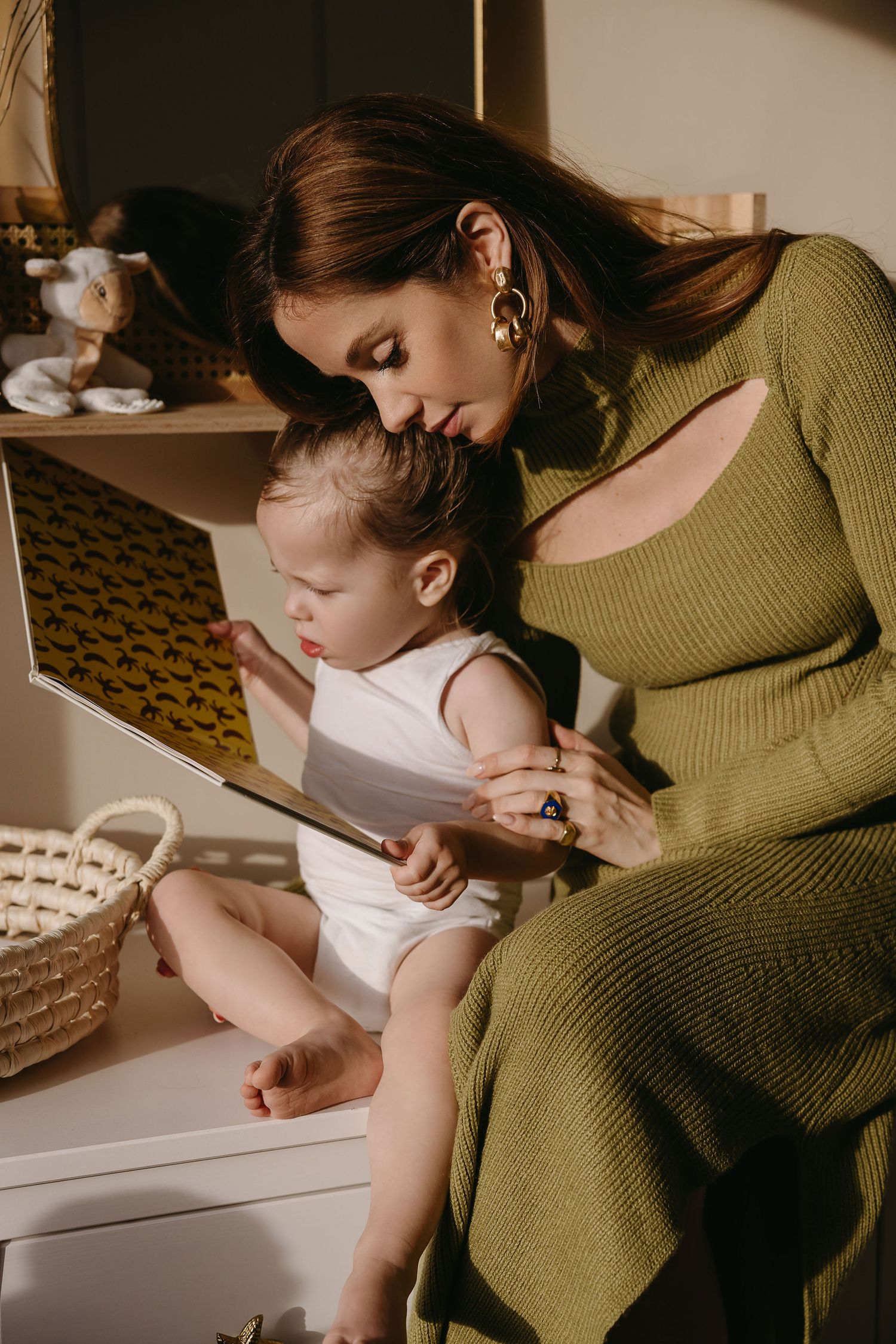 An intimate moment shared while reading together on a white dresser in warm lighting.