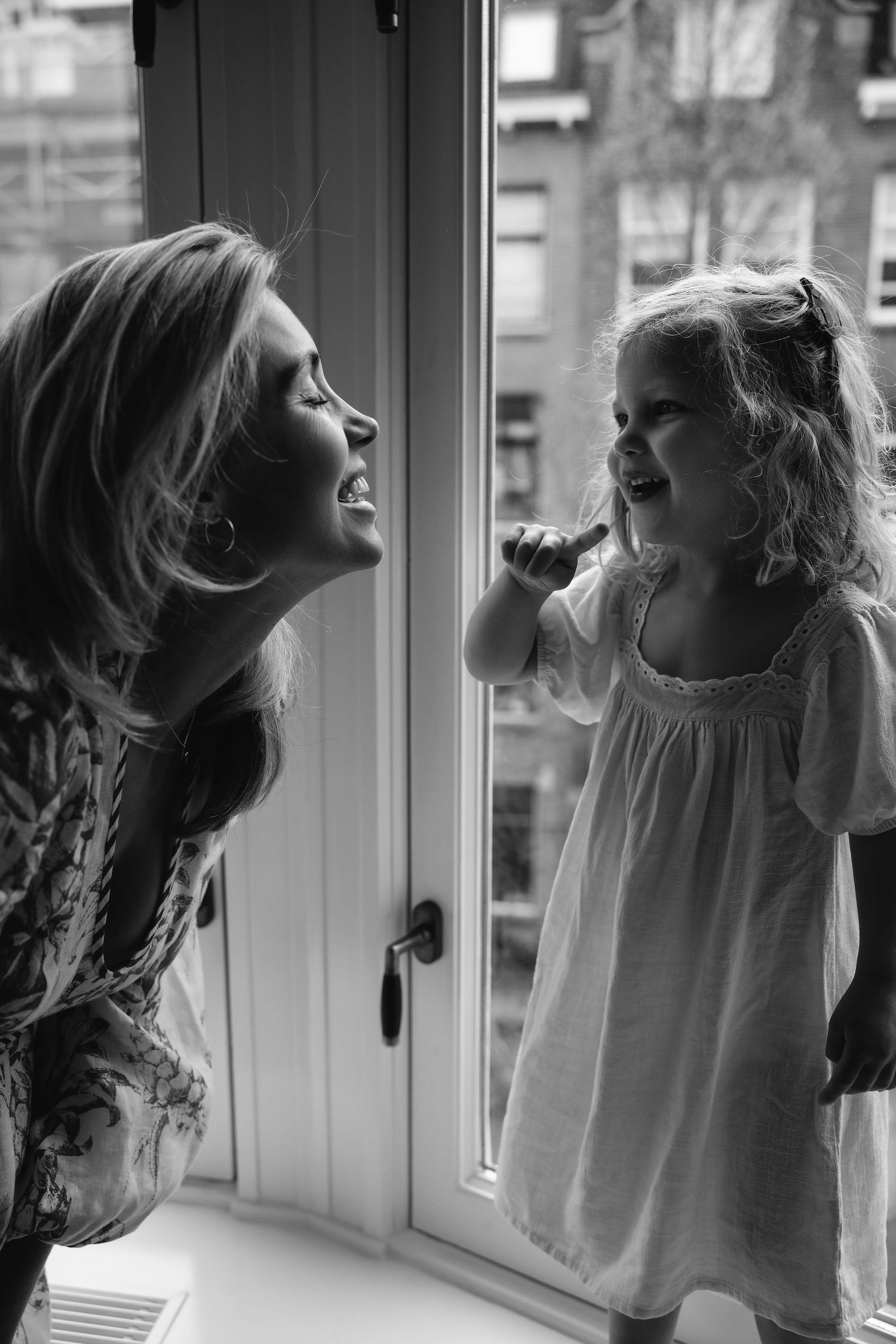 Black and white photo of joyful moment by window.