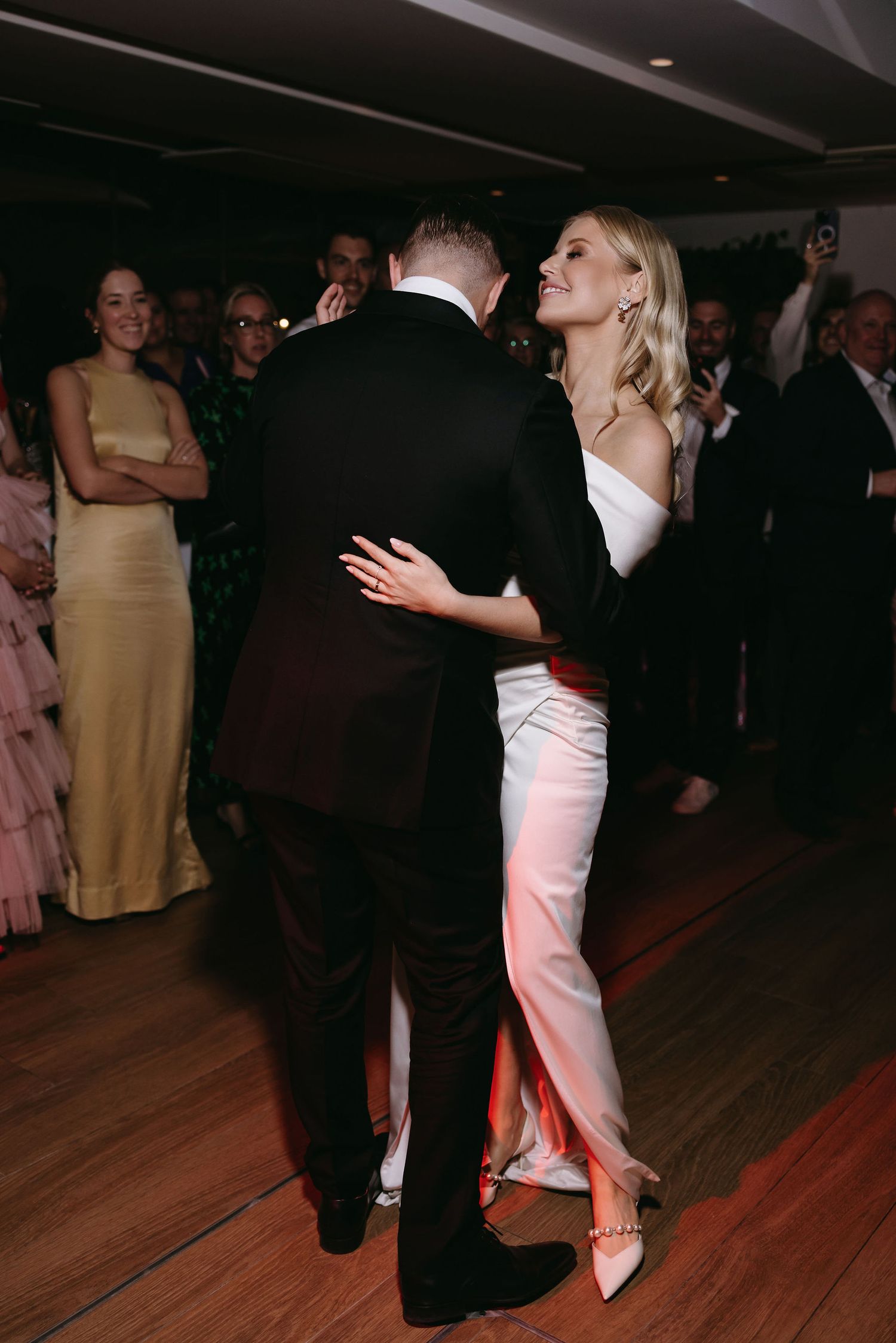 Couples dancing together on a wooden dance floor at an elegant evening event with dark ambiance and formal attire.