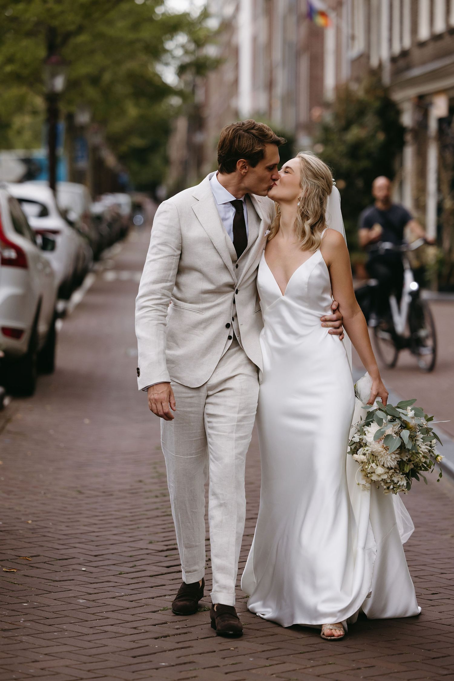 Romantic moment between newlyweds on Amsterdam street with bride holding bouquet.