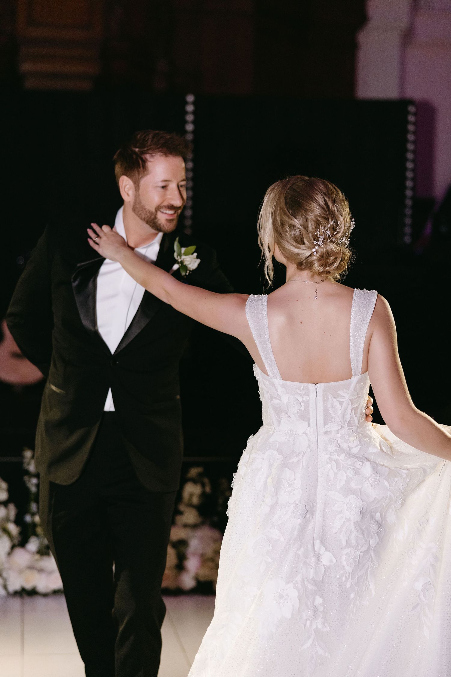 Bride and groom share their first dance at wedding reception, with her white dress flowing elegantly.