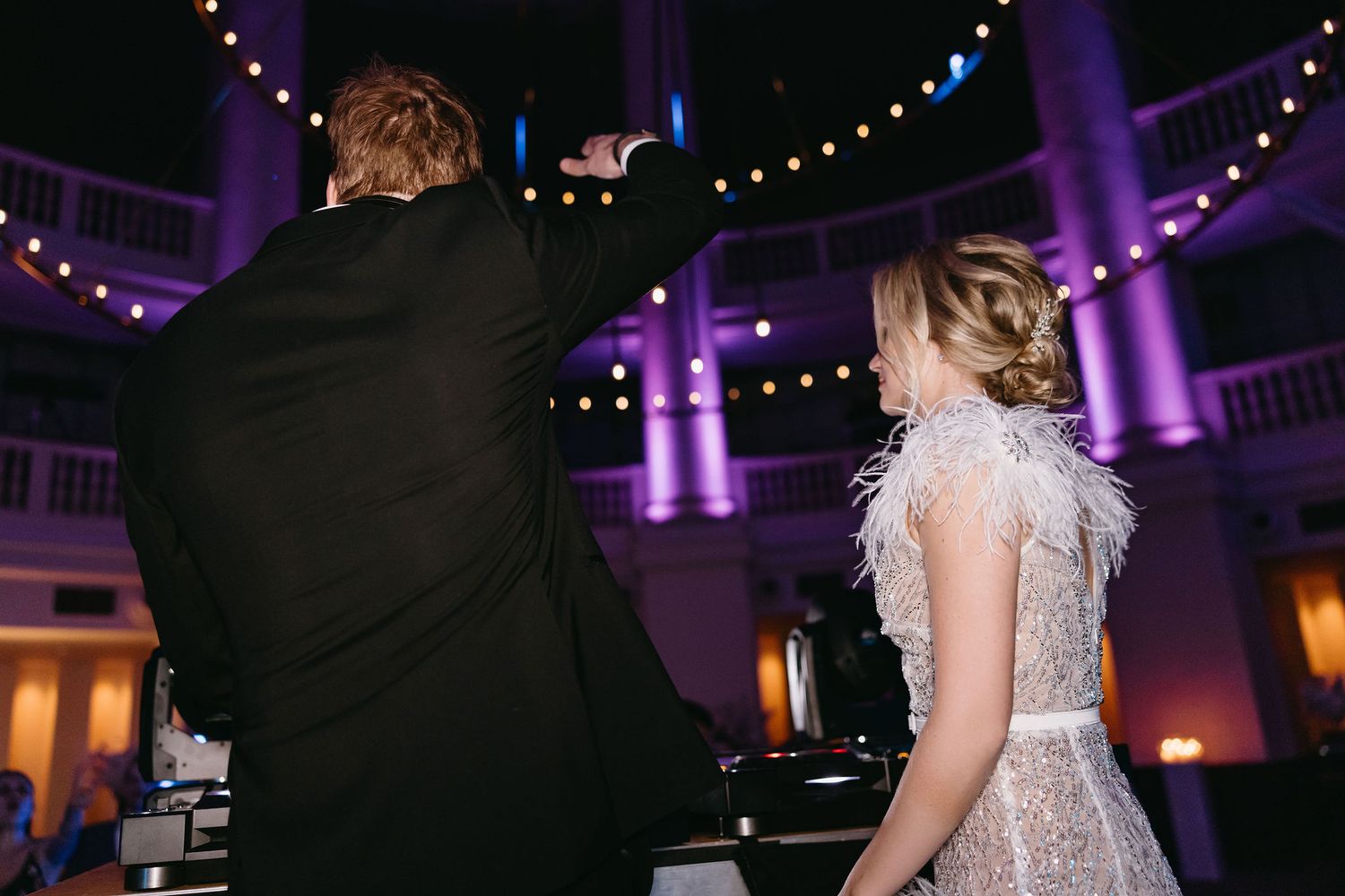 Wedding reception venue with purple uplighting and string lights creating a magical atmosphere.