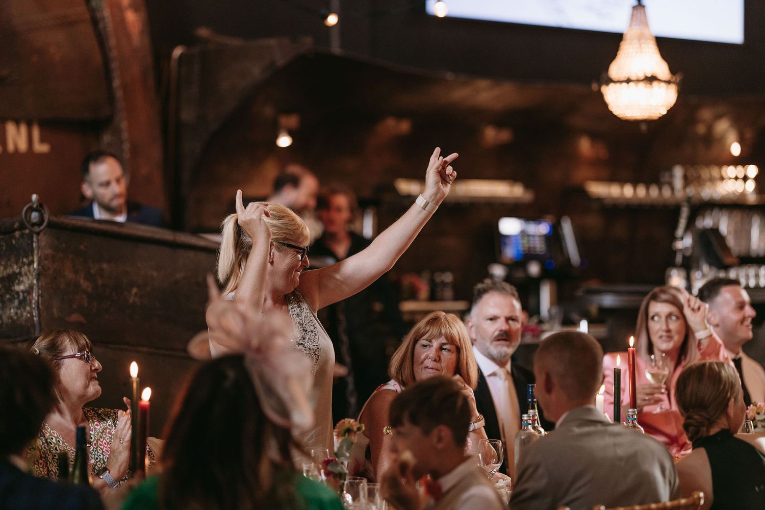 Wedding celebration with guests dancing energetically in a dimly lit reception venue.