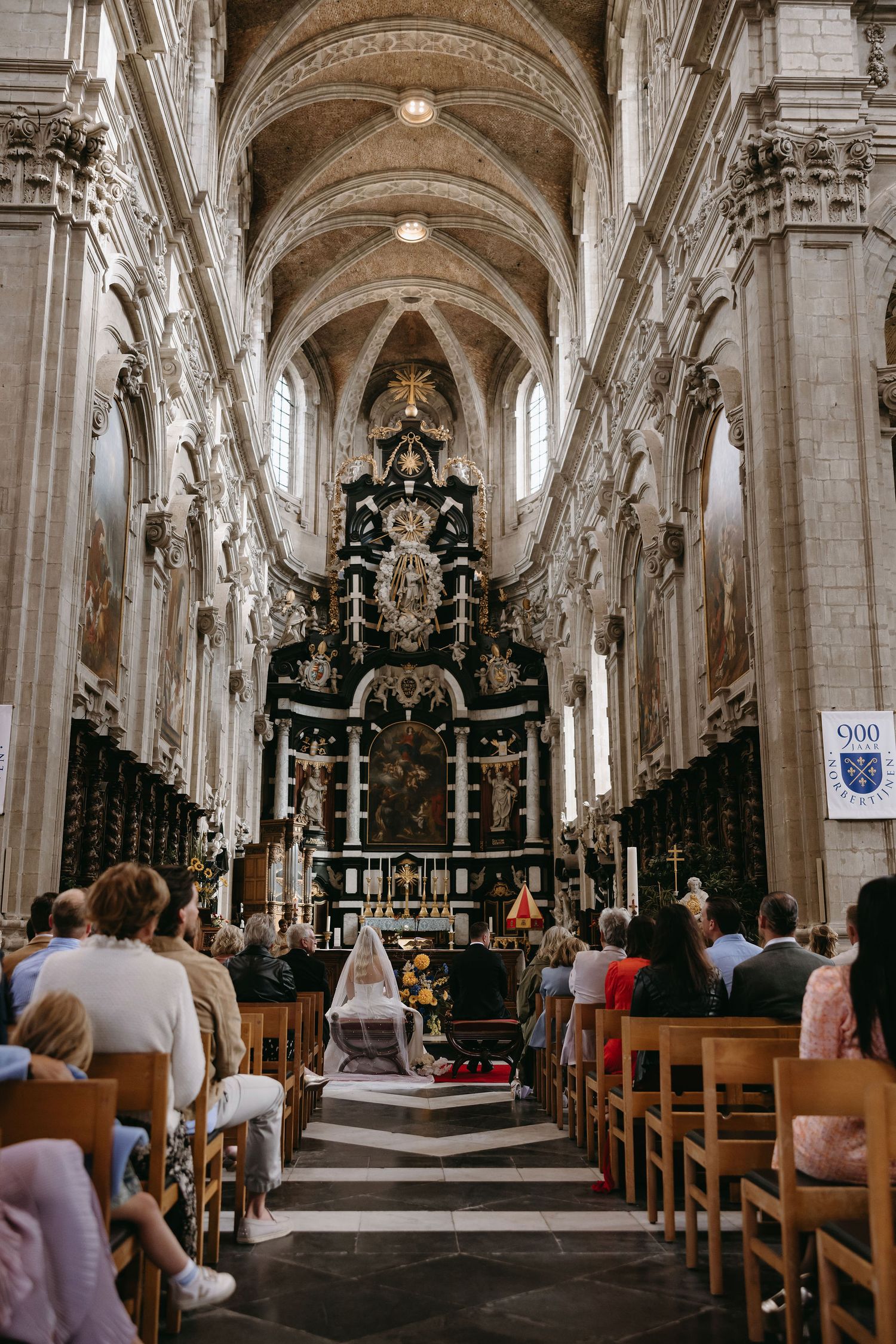 A cathedral interior with vaulted ceilings and ornate altar during a wedding ceremony.