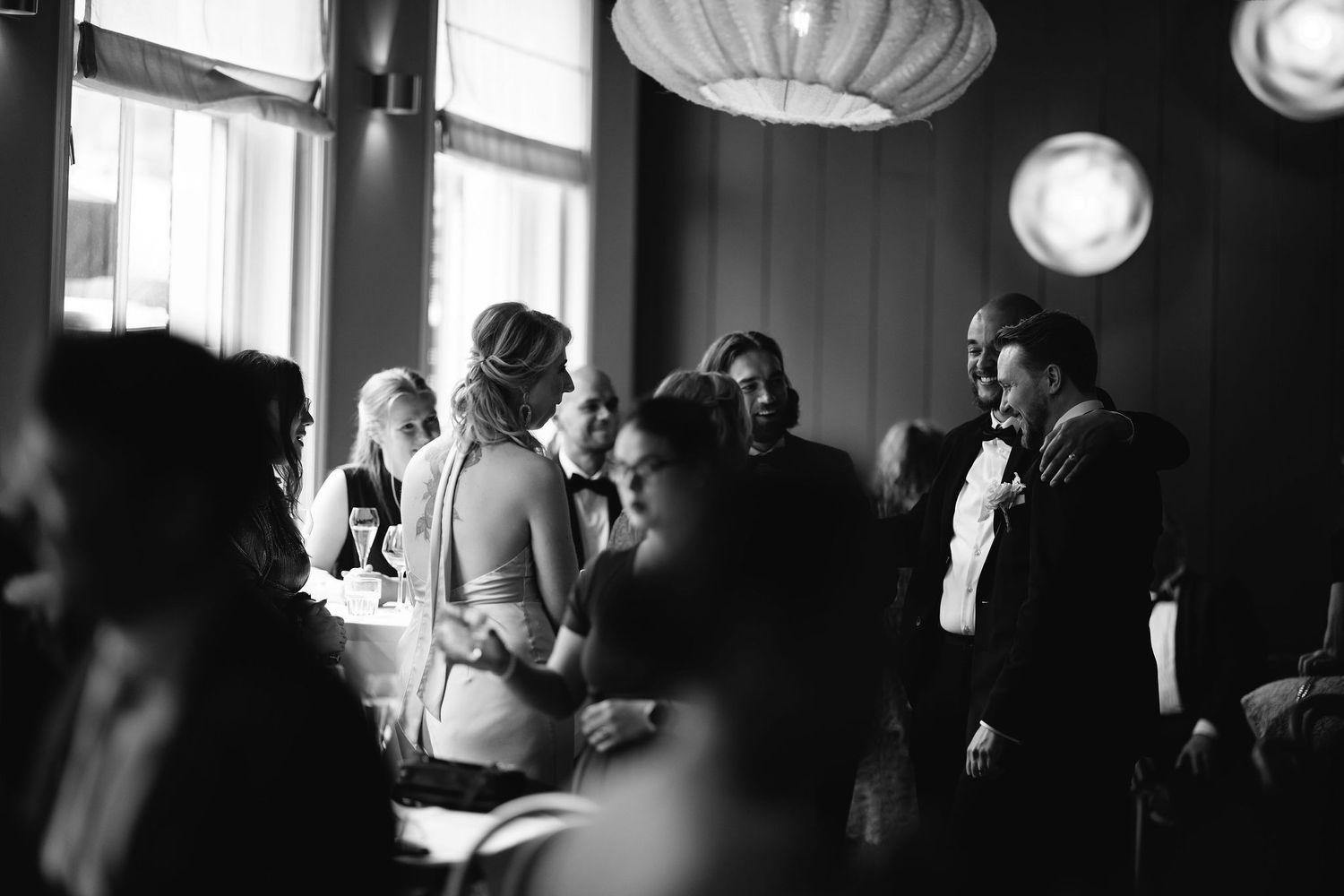 Moody black and white reception venue photo with ambient lighting and paper lanterns.