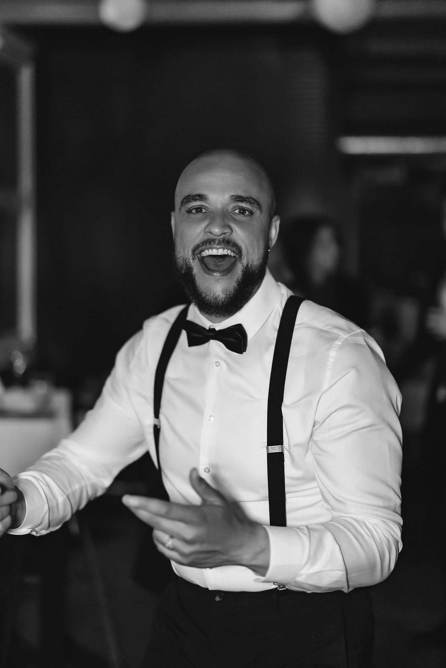 A joyful guest in suspenders and bowtie dancing at a wedding reception.