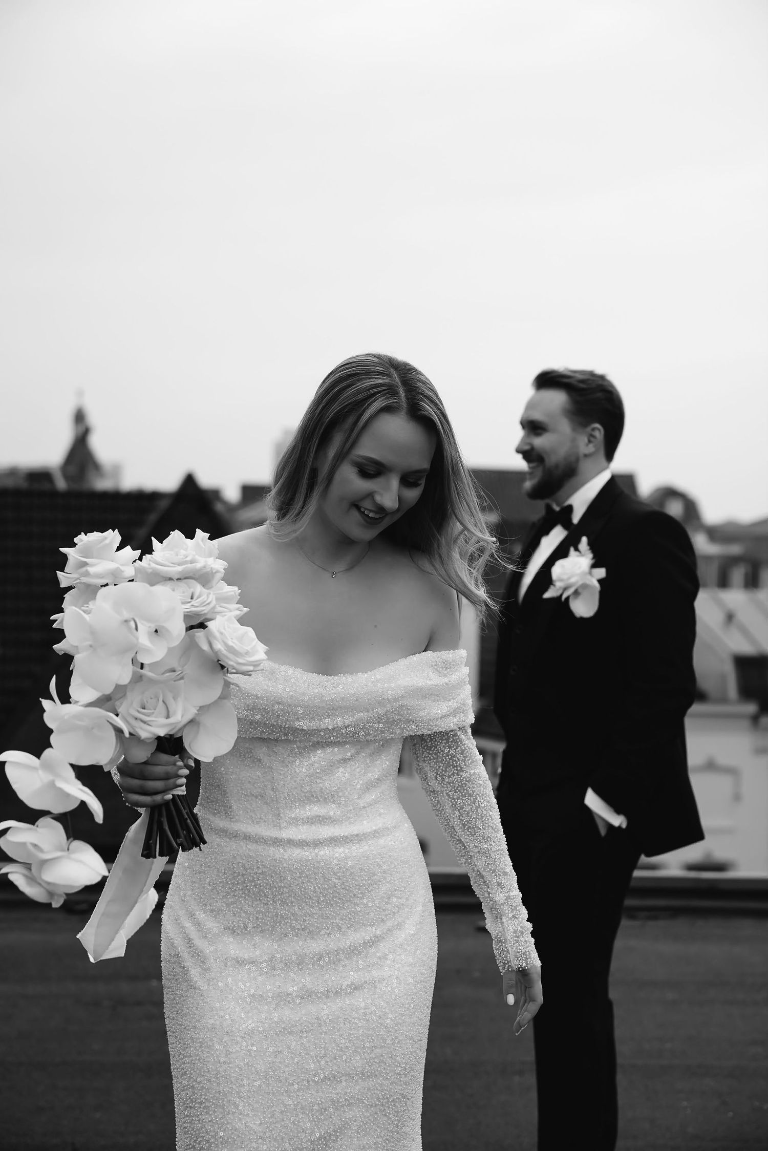 Joyful wedding moment captured in black and white with white orchid bouquet.