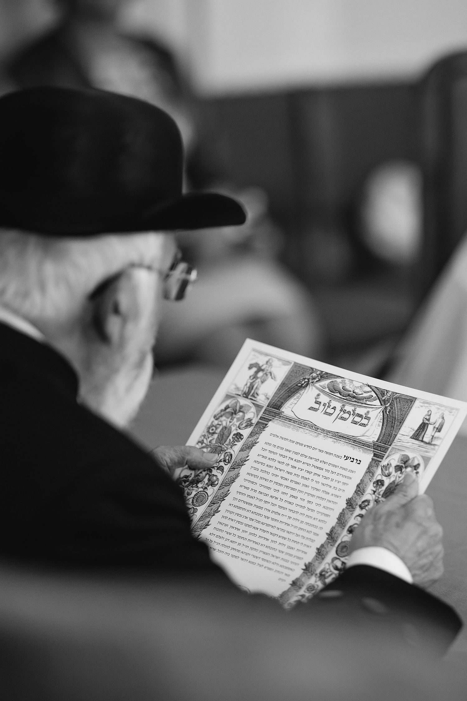 Black and white image of someone reading from a decorative text during ceremony.