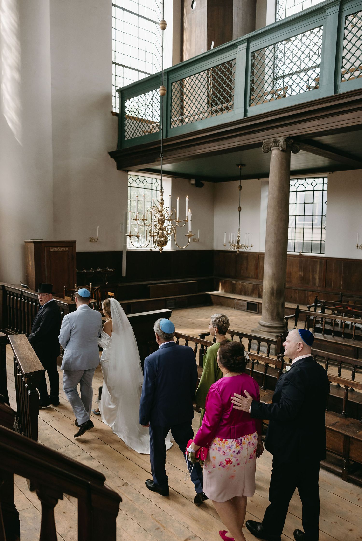 Interior view of historic church with wooden pews and balcony during wedding ceremony.
