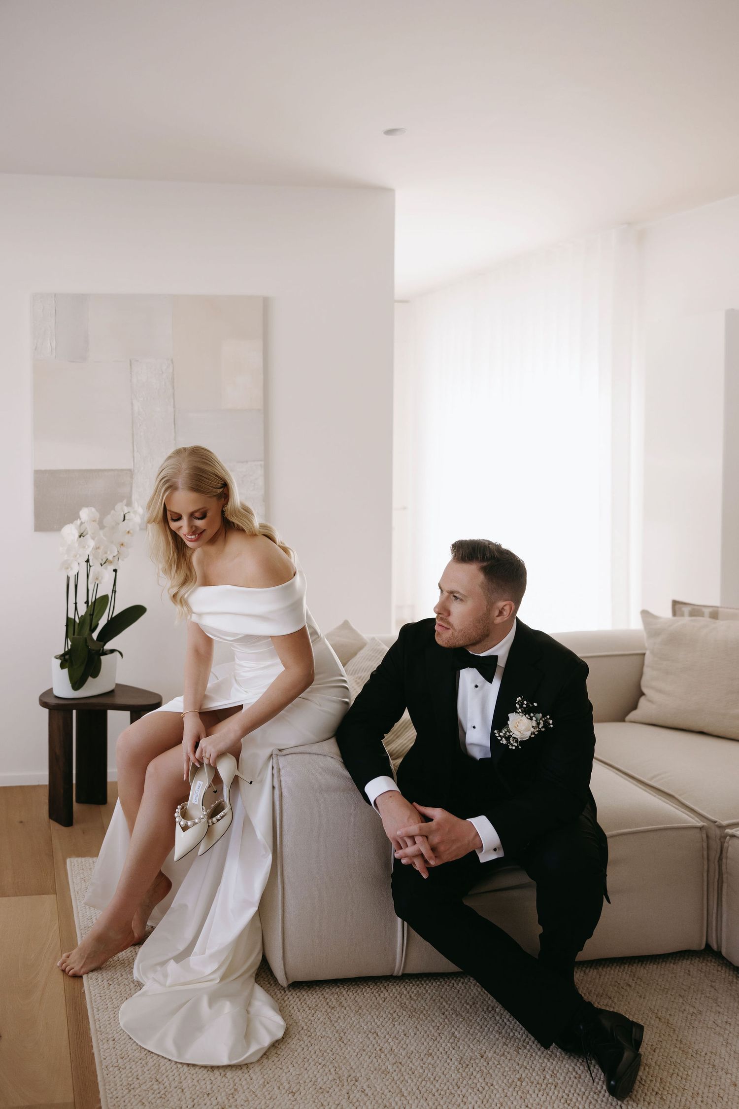 A couple sharing a candid moment in their formal attire in a bright modern room.