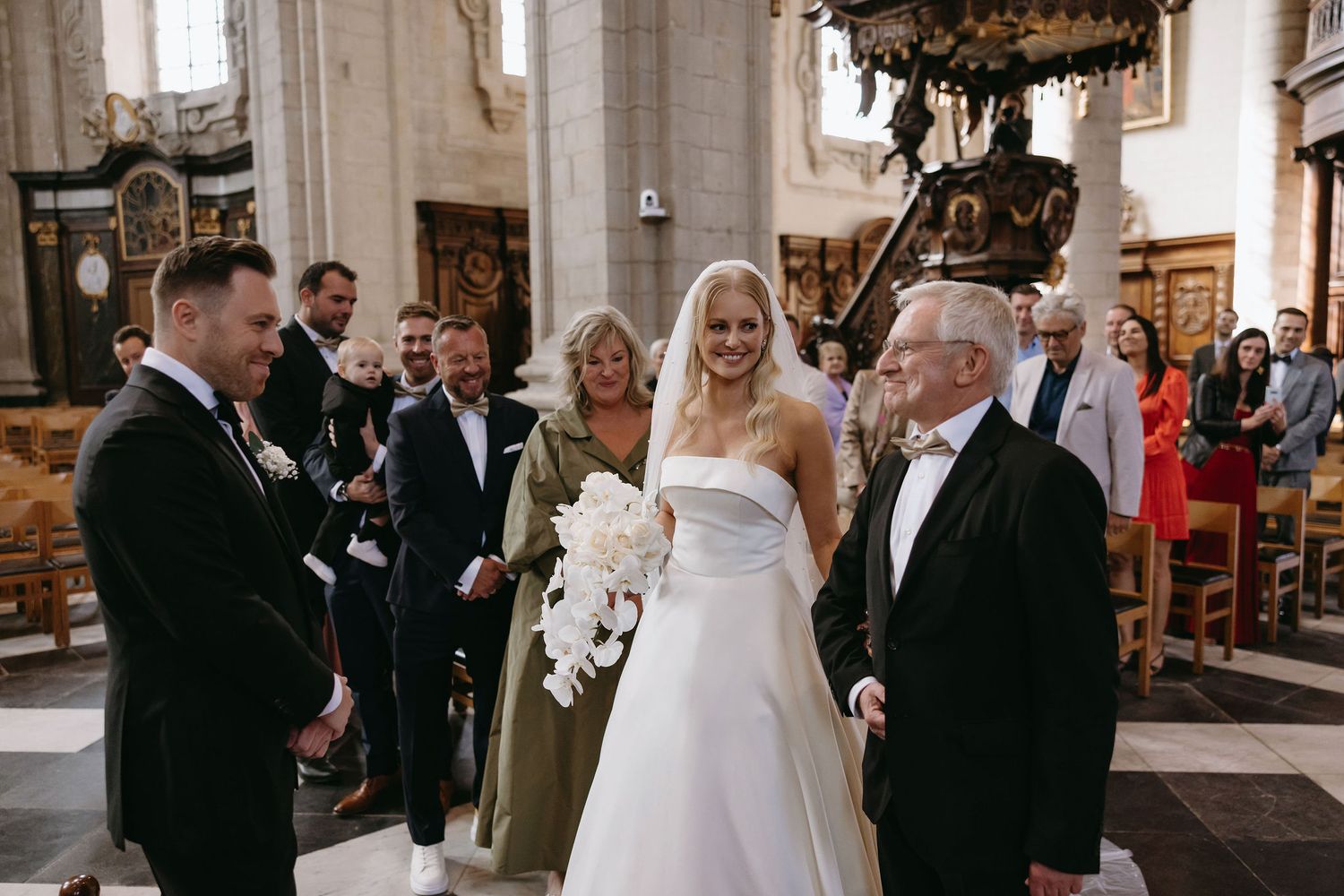 Wedding party gathers inside ornate church during ceremony.
