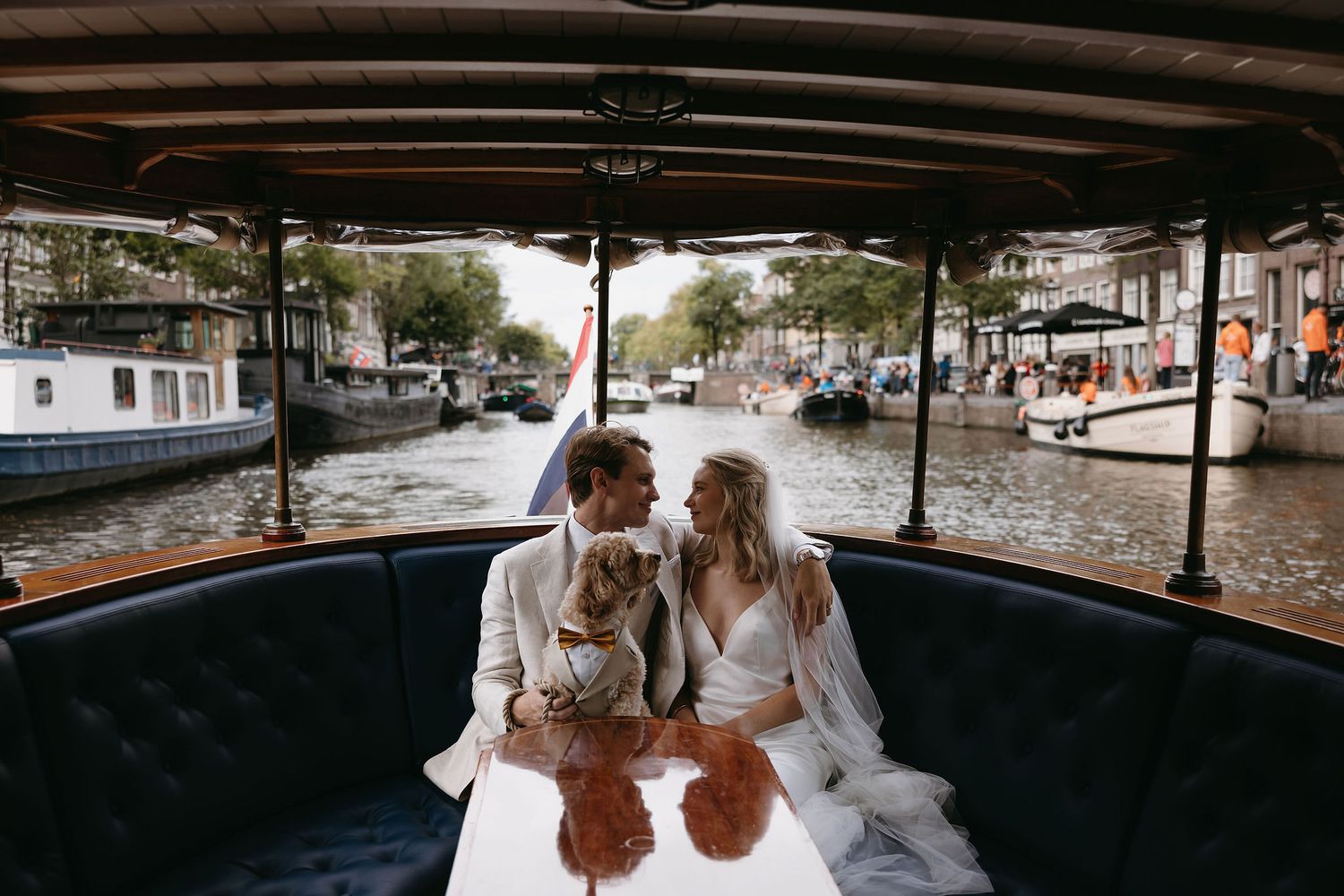 Couple sharing intimate moment on cushioned seat of vintage boat in Amsterdam.