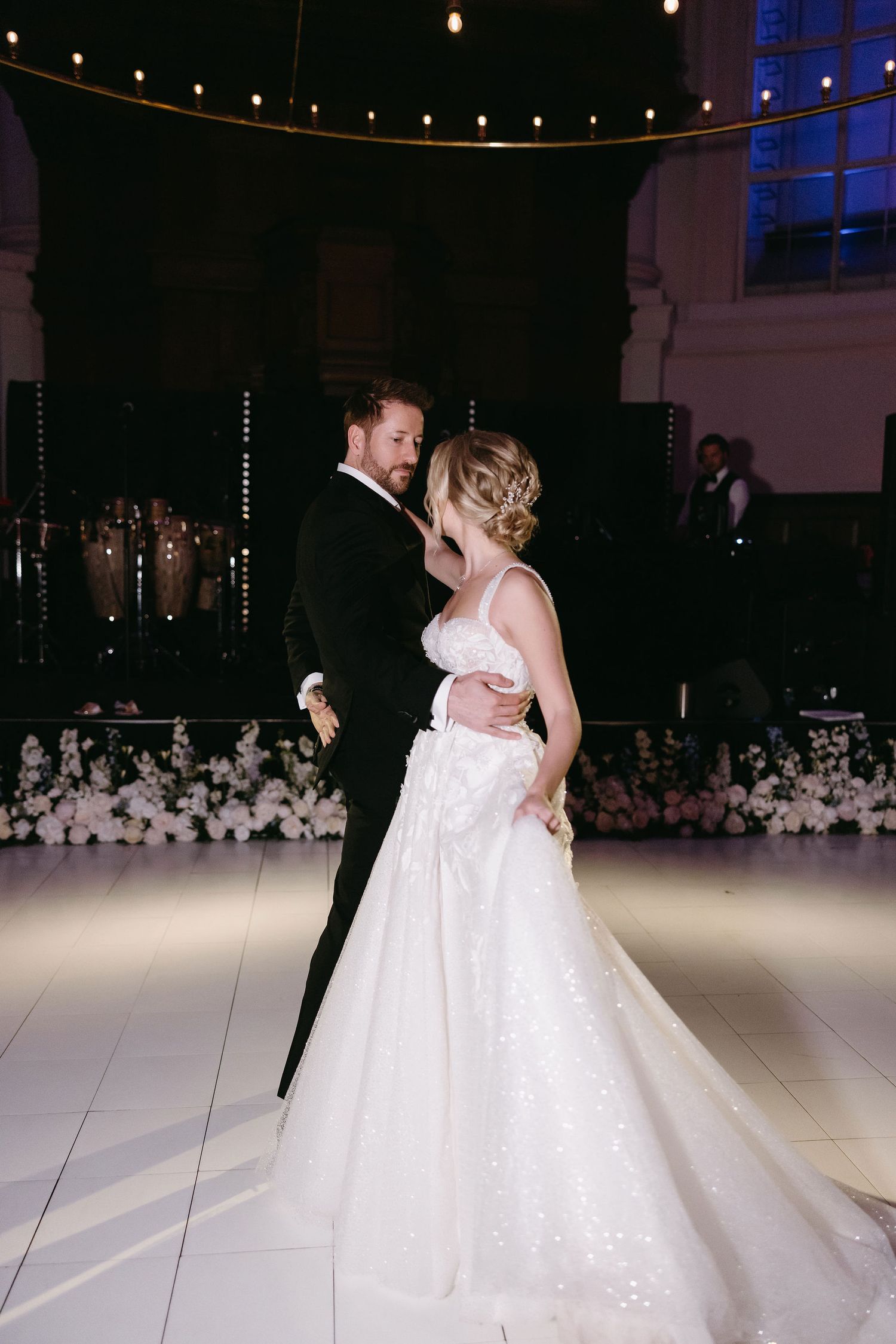 Romantic dance moment captured at wedding reception with string lights in background.