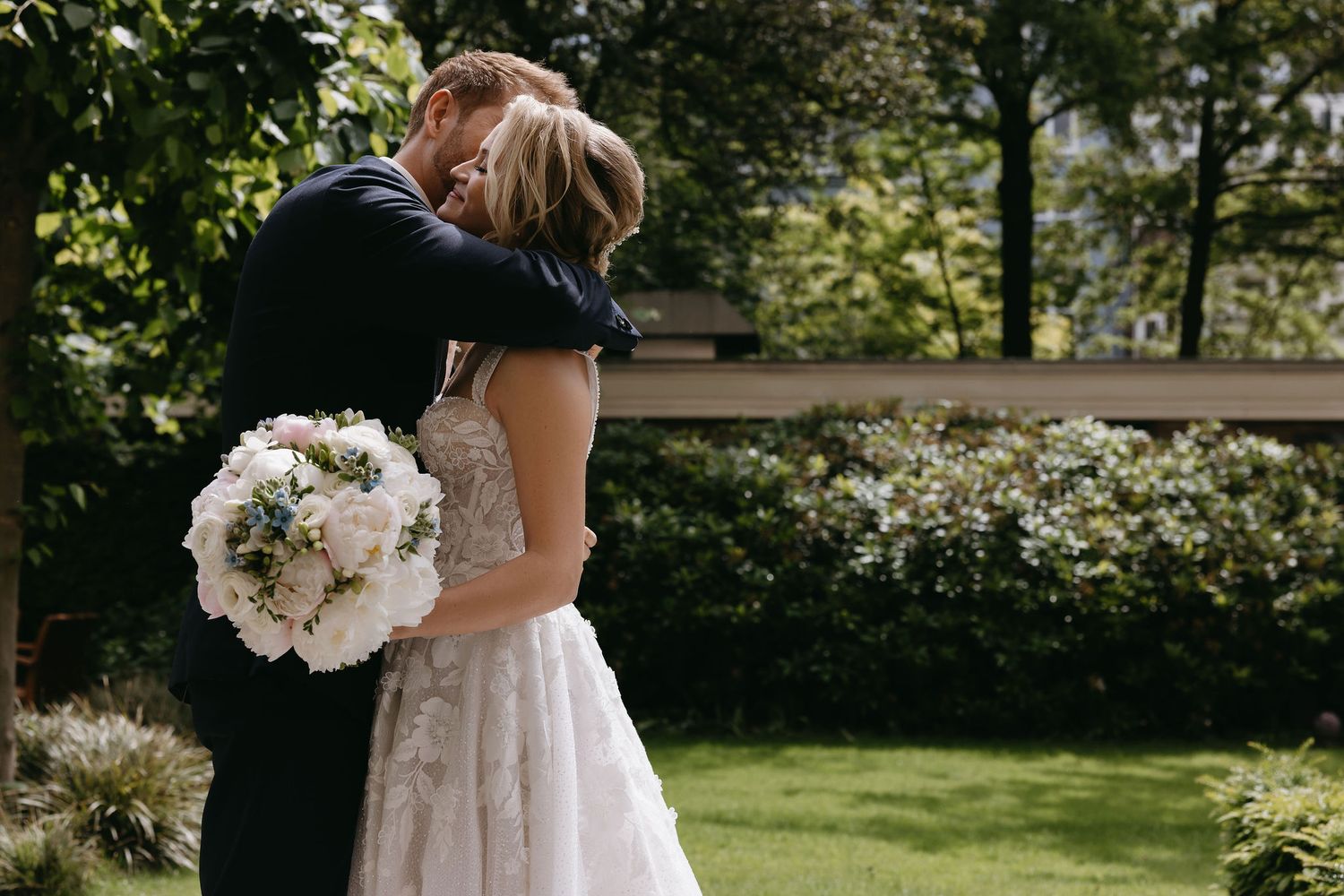 Outdoor garden wedding ceremony with white floral arrangements and natural lighting.