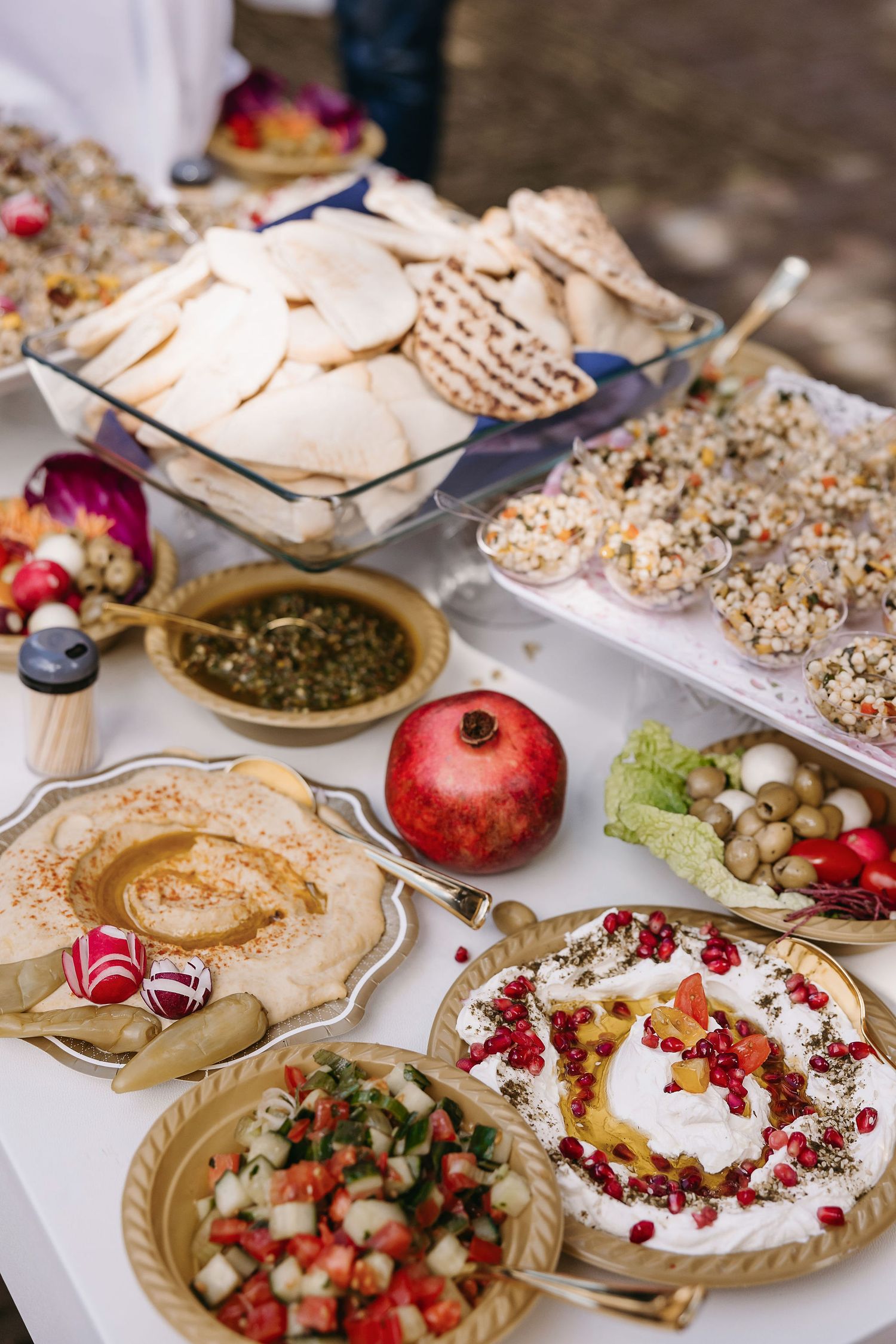 Colorful spread of Mediterranean appetizers including hummus, pomegranate, and various dips.