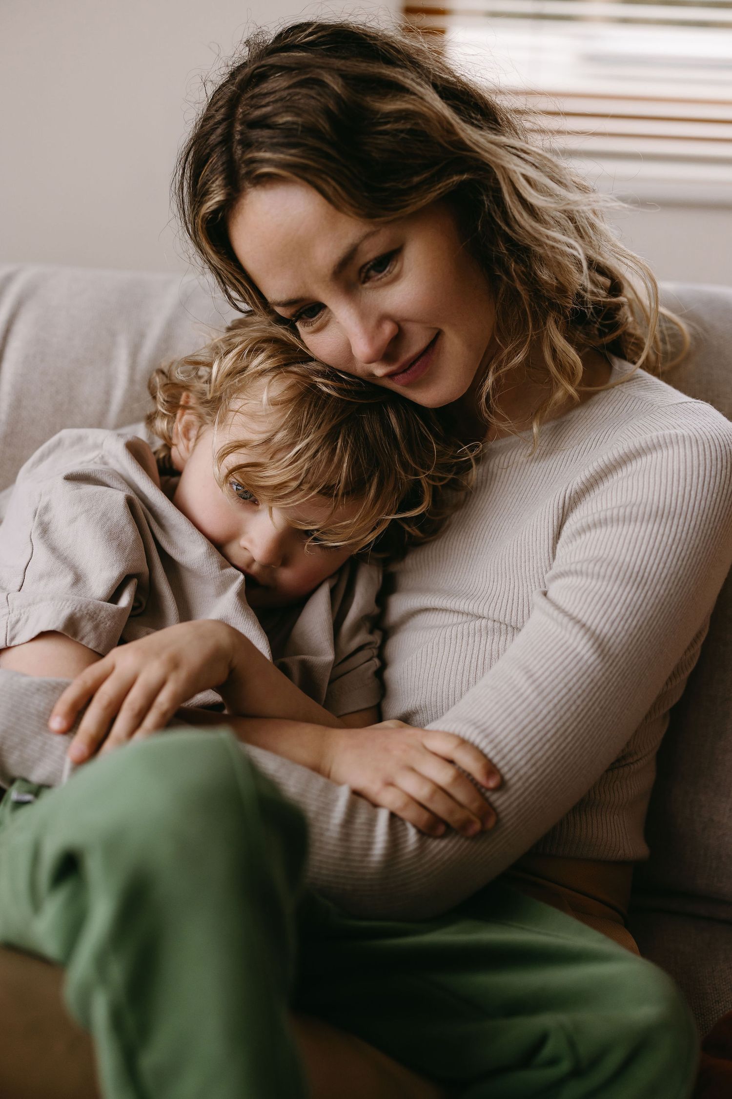 Warm and intimate lifestyle photos of family cuddling on couch in natural light.