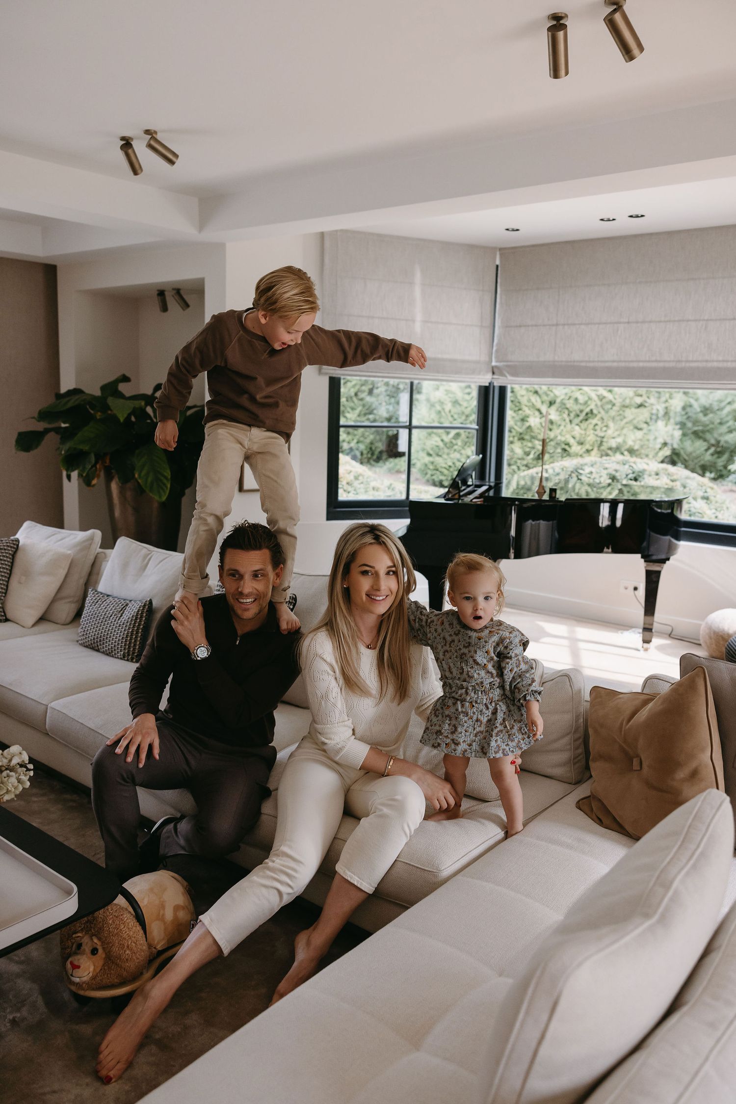 Casual family scene on modern white sectional sofa in bright living room.