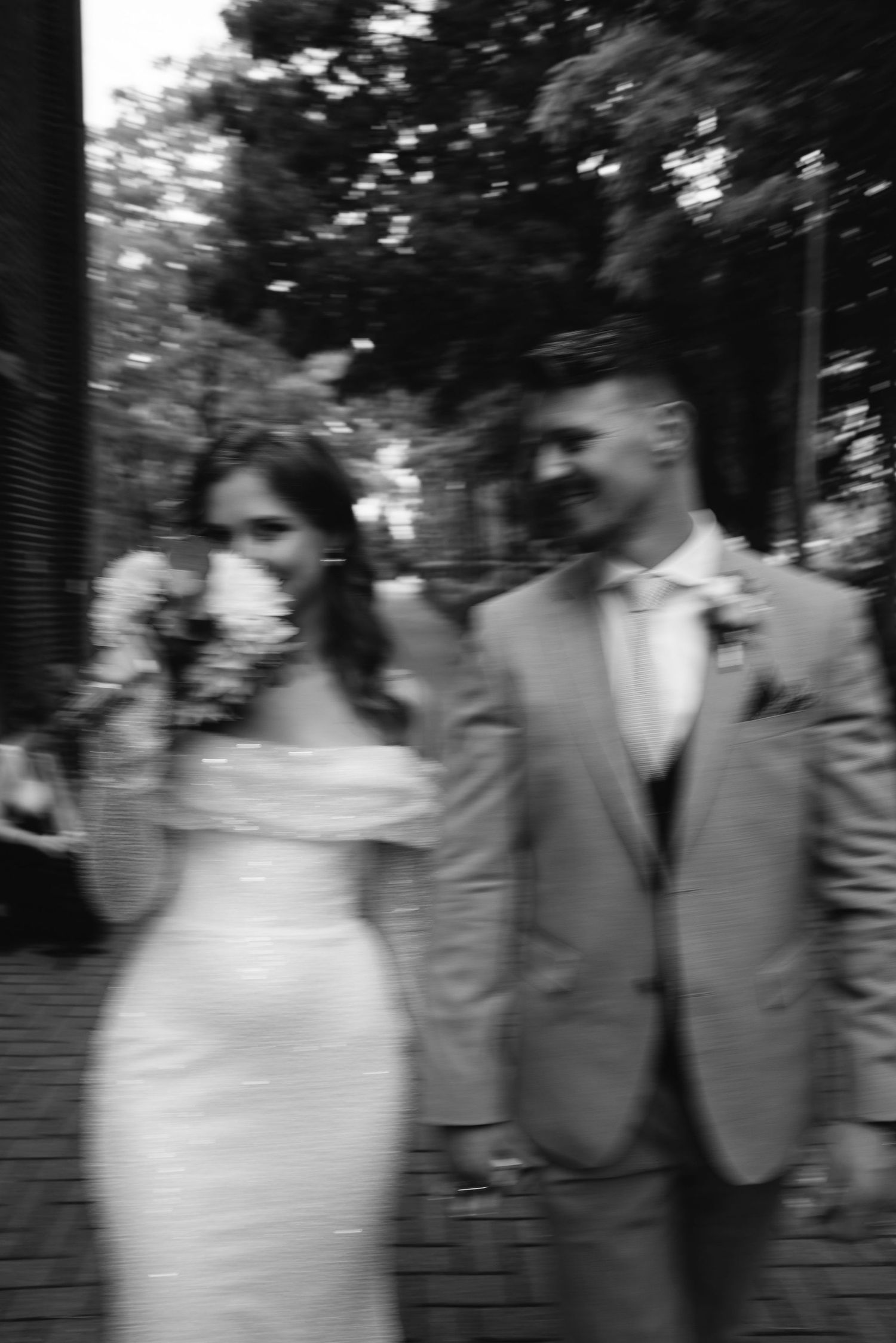 Artistic black and white motion blur of wedding party members walking outdoors.