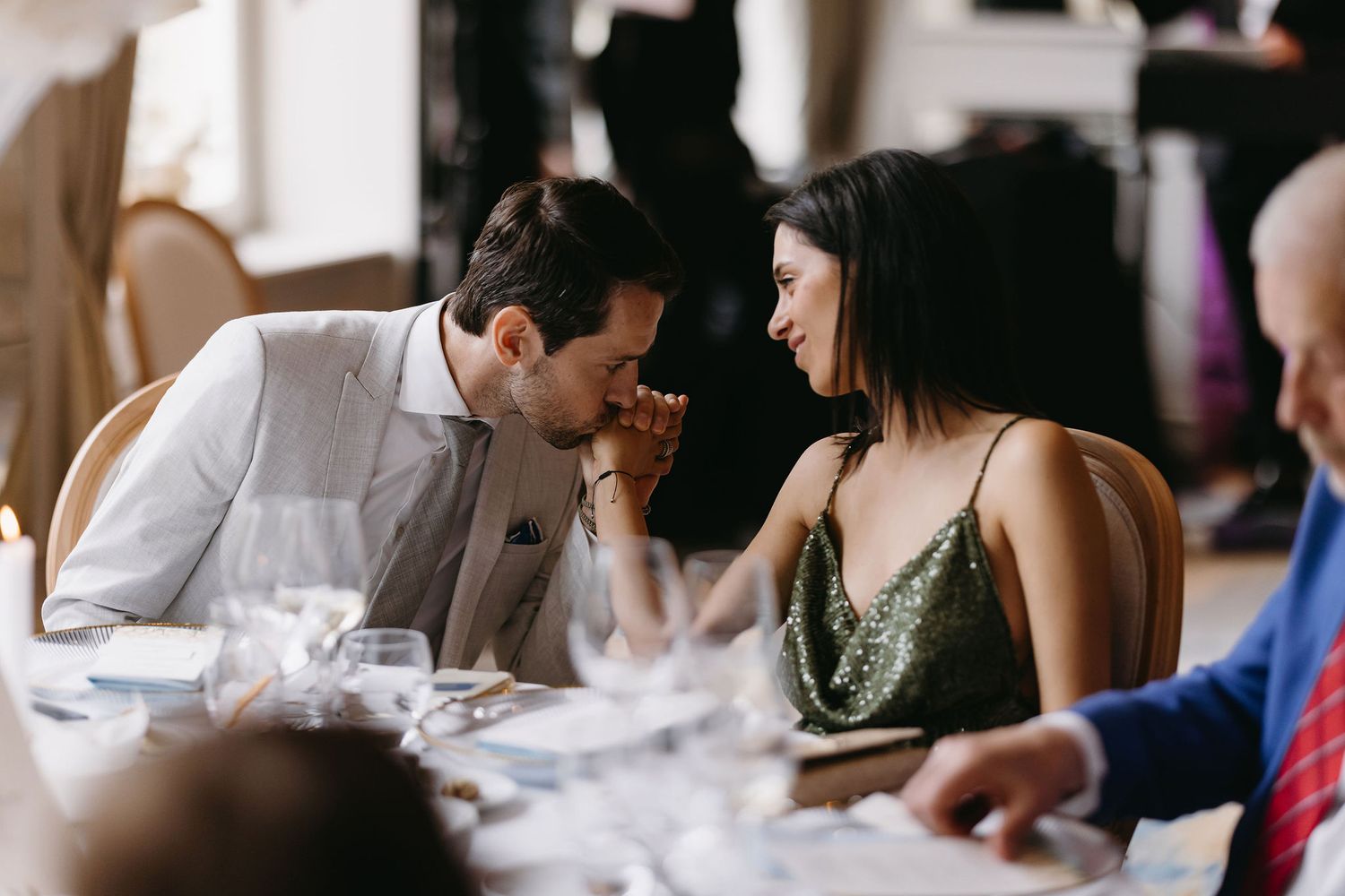 A couple shares an intimate moment during dinner at an elegant restaurant setting.