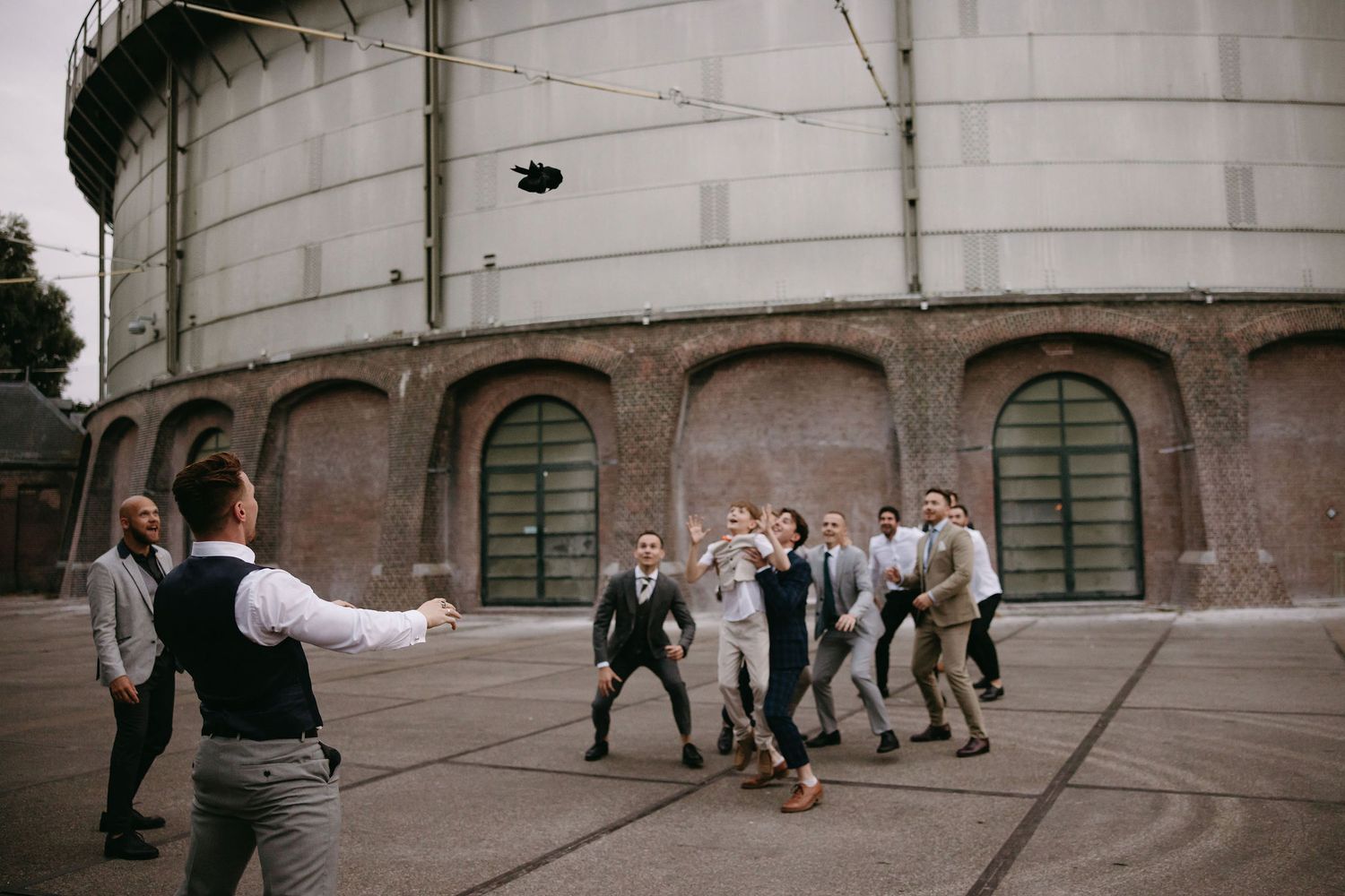 Wedding party playing games and having fun in an outdoor stone courtyard.