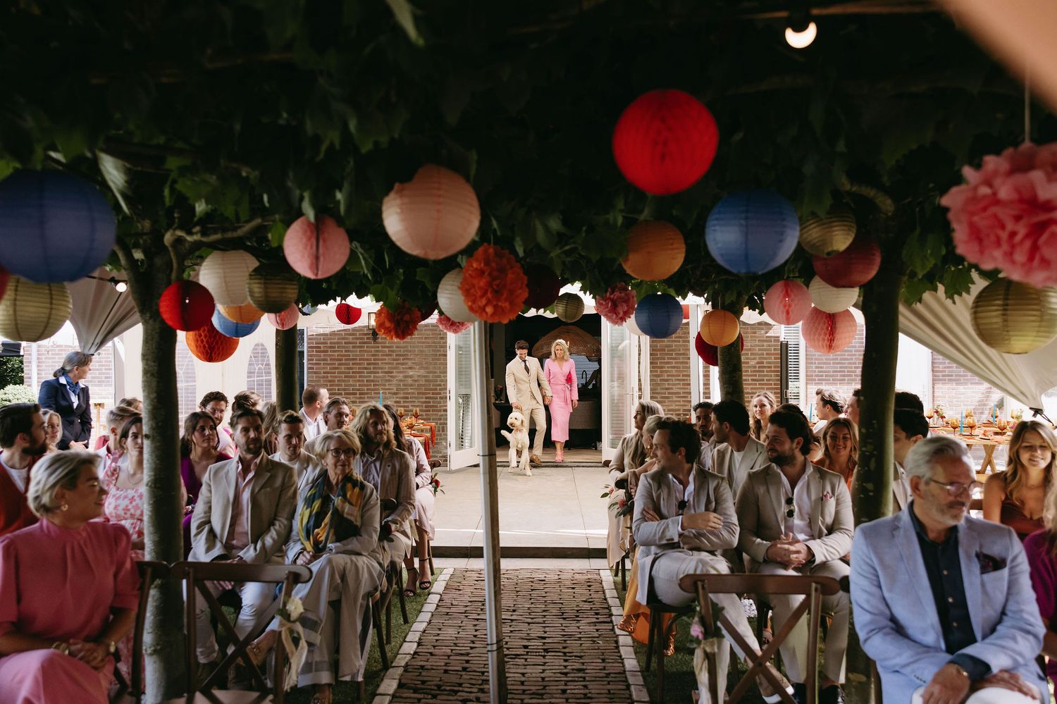 Outdoor wedding ceremony setup with colorful lanterns hanging overhead.