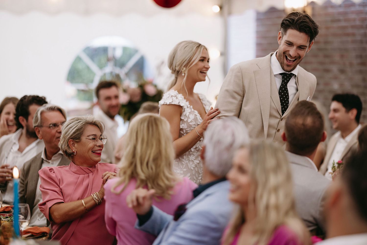 Candid moment of laughter during wedding reception under tent.