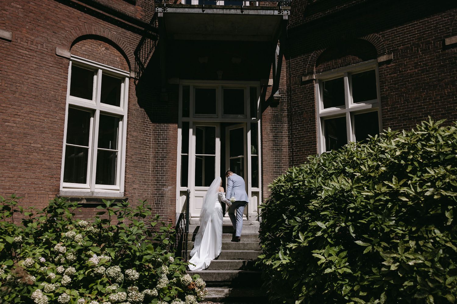 Brick building exterior with windows and greenery in a clean architectural composition.