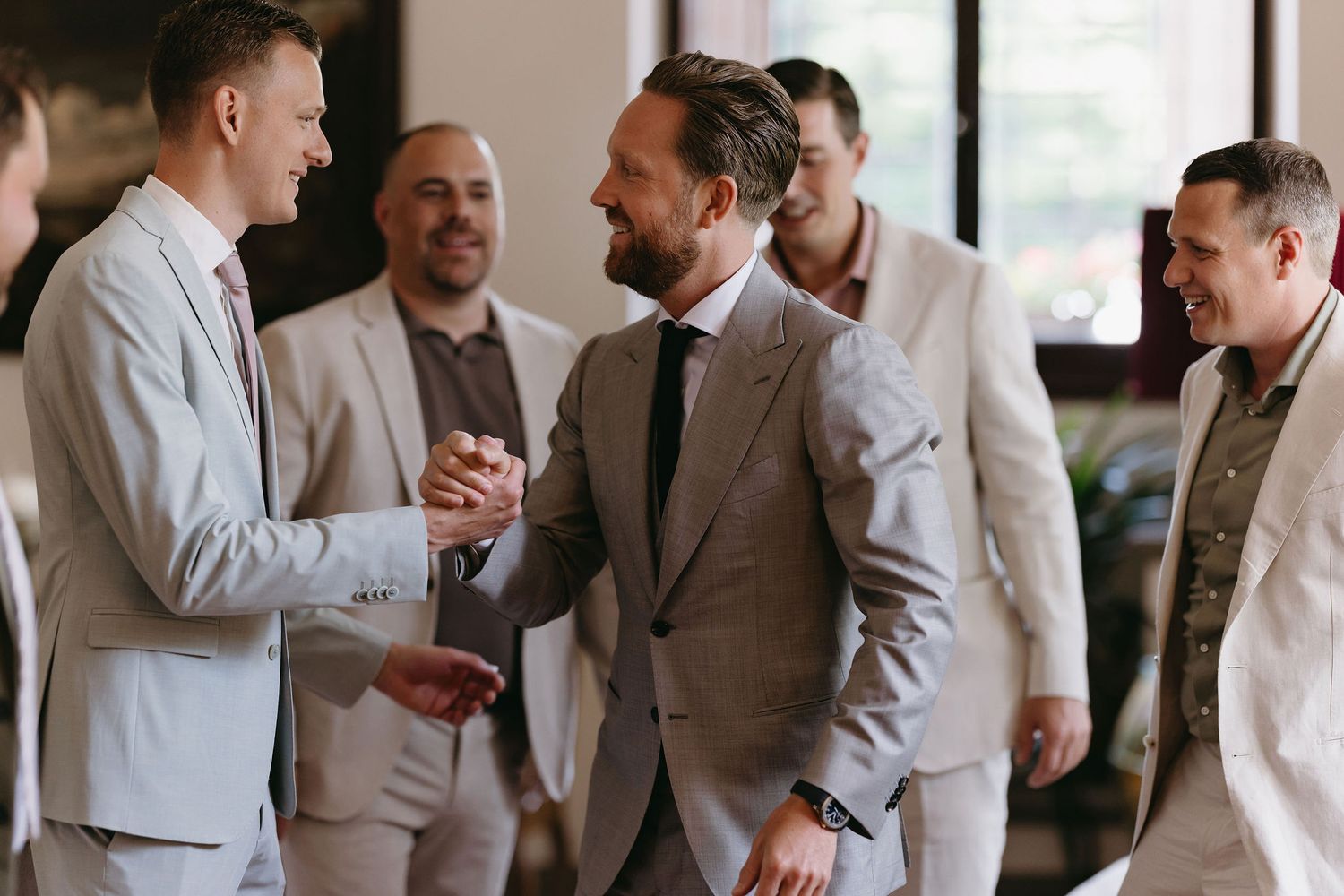 A group of well-dressed men in suits sharing a joyful moment during a formal gathering.