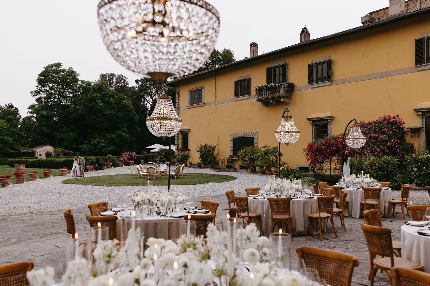 Elegant wedding reception setup with crystal chandeliers and table settings at Italian villa.