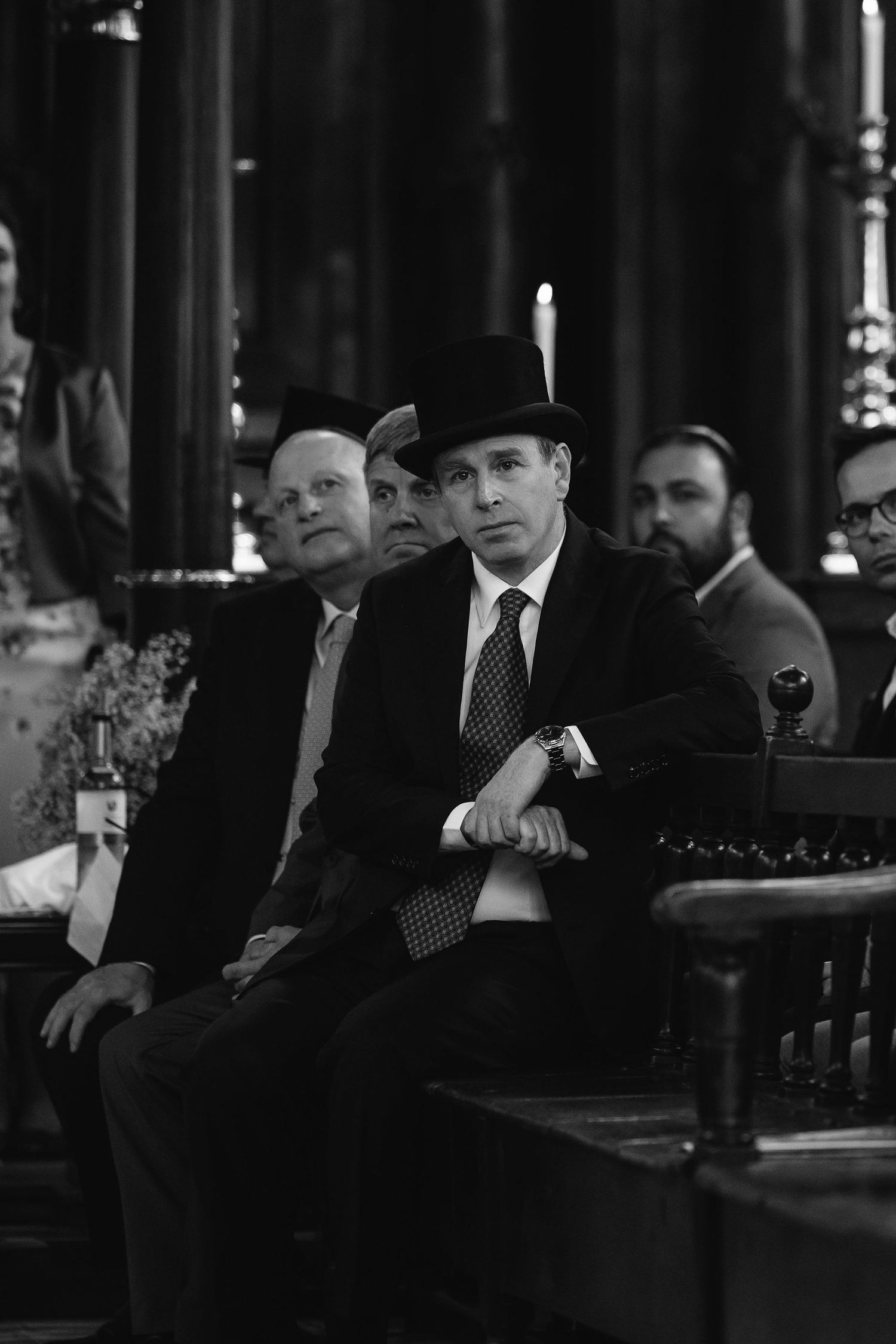 Black and white photograph showing men in suits seated at dining tables in an elegant setting.