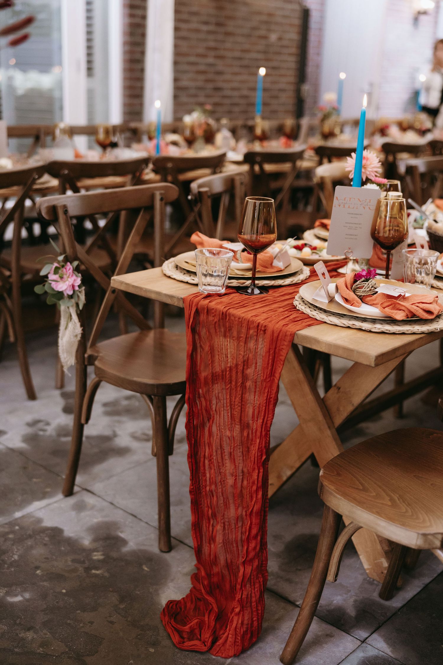 Reception tables set with red table runners and place settings for wedding celebration.