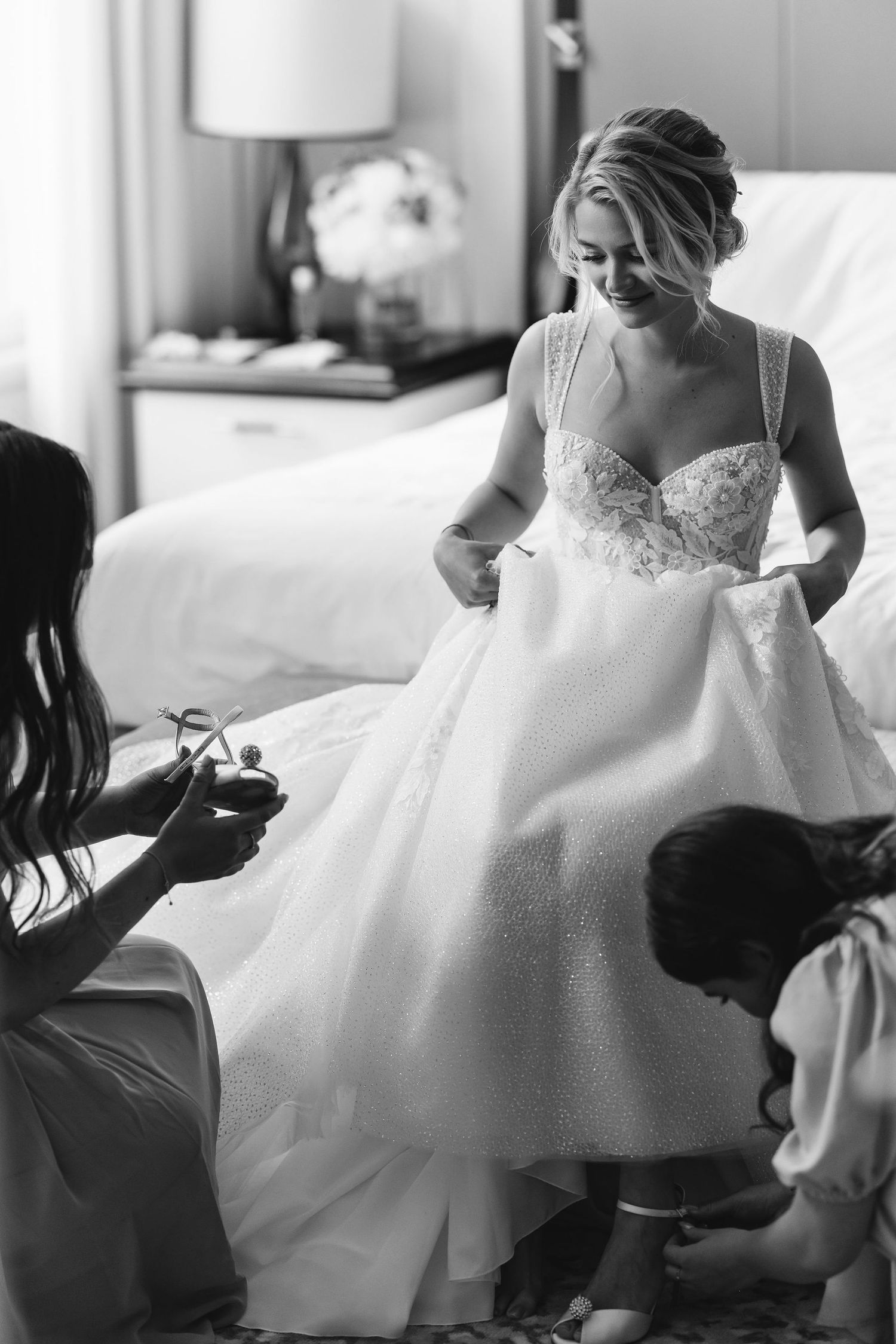 Black and white getting ready scene with flowing white wedding dress.
