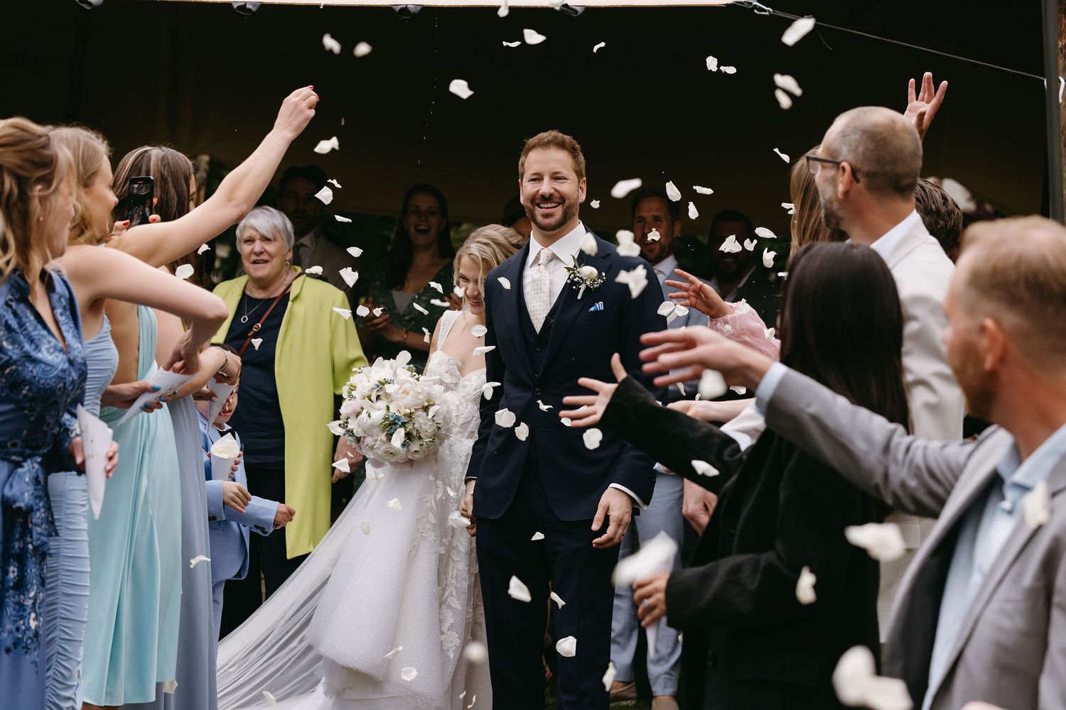 Wedding guests throwing confetti during a joyous celebration outdoors.
