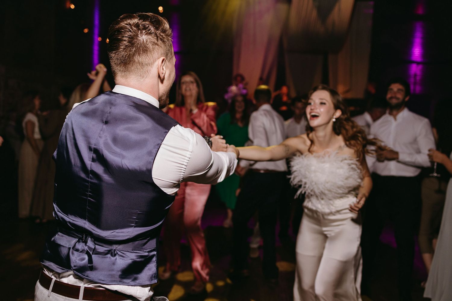Dancing couple enjoying lively moments on the wedding reception dance floor.