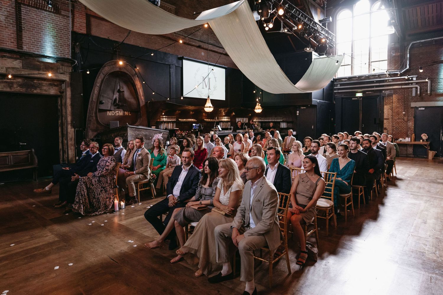 Panoramic shots of wedding guests seated in rows during an indoor ceremony.