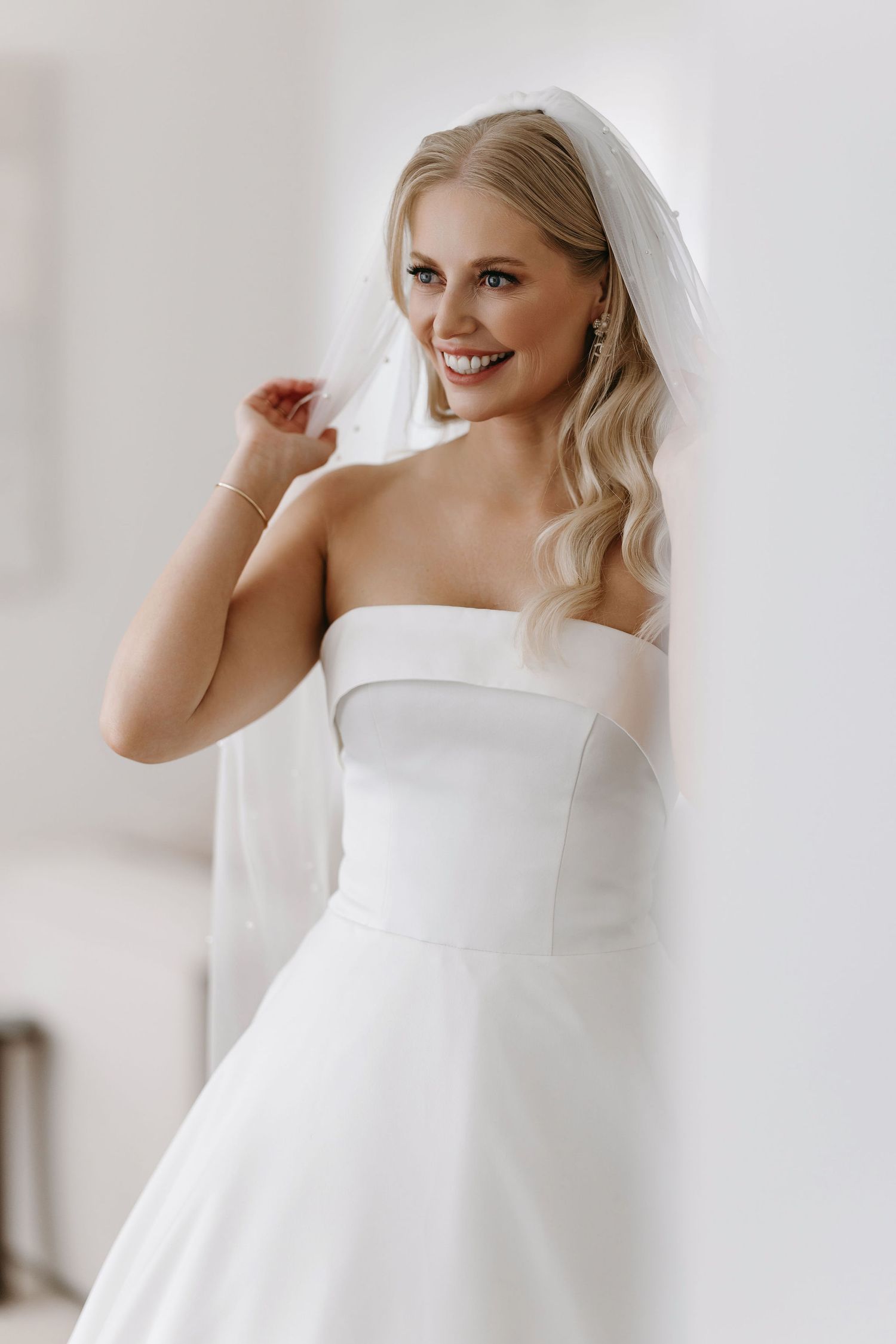 Classic elegant strapless white wedding gown with a flowing A-line silhouette and delicate veil.