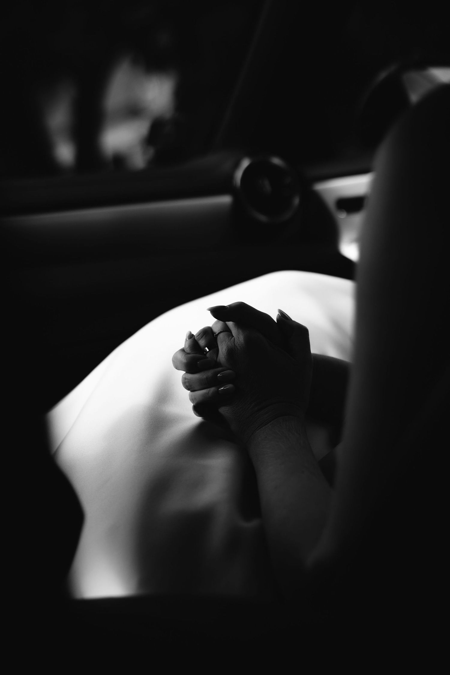 Artistic black and white closeup of hands holding a rose against white fabric.