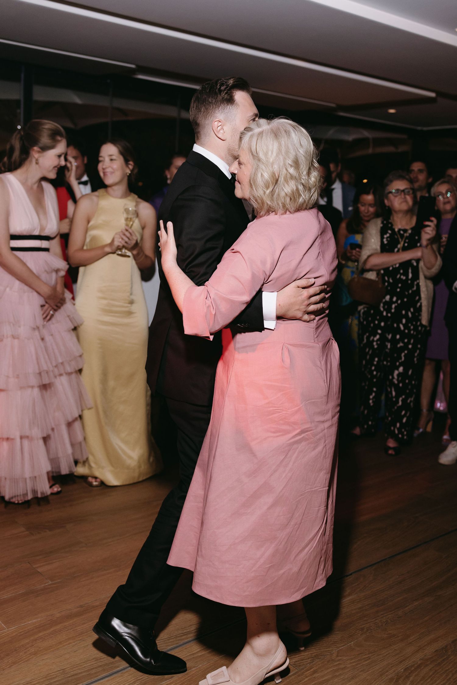 Wedding reception dance features couples in formal attire on a wooden dance floor.