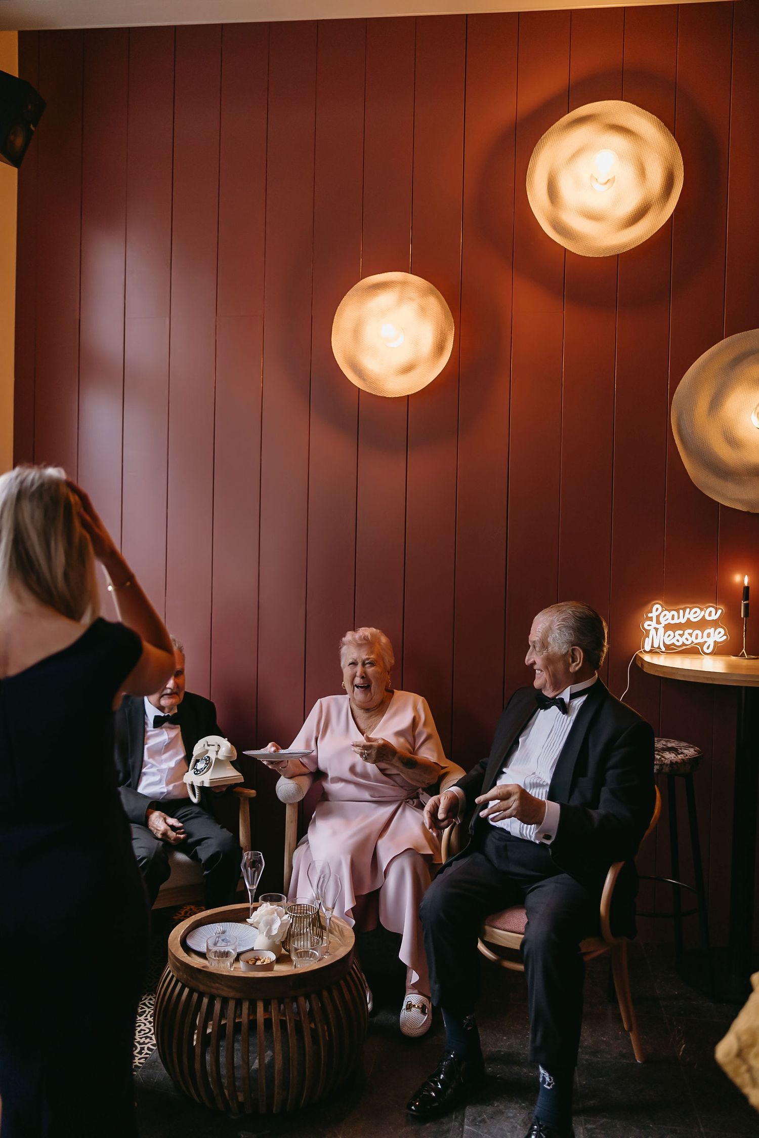 Warm-lit interior scene with guests relaxing in vintage decor with circular wall lights.
