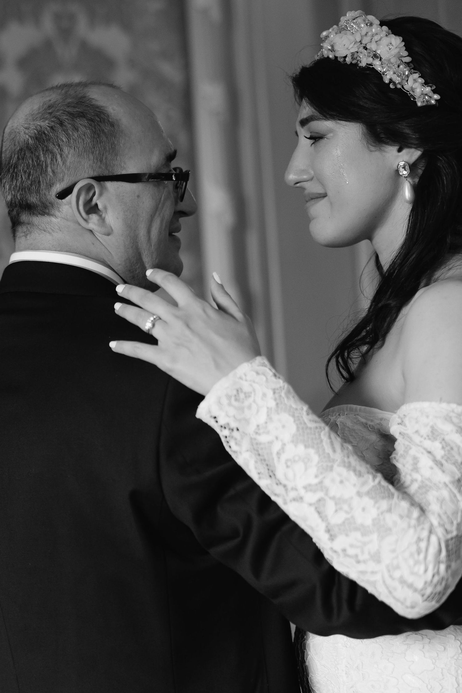 A tender black and white photograph capturing an intimate father-daughter dance moment at a wedding reception.